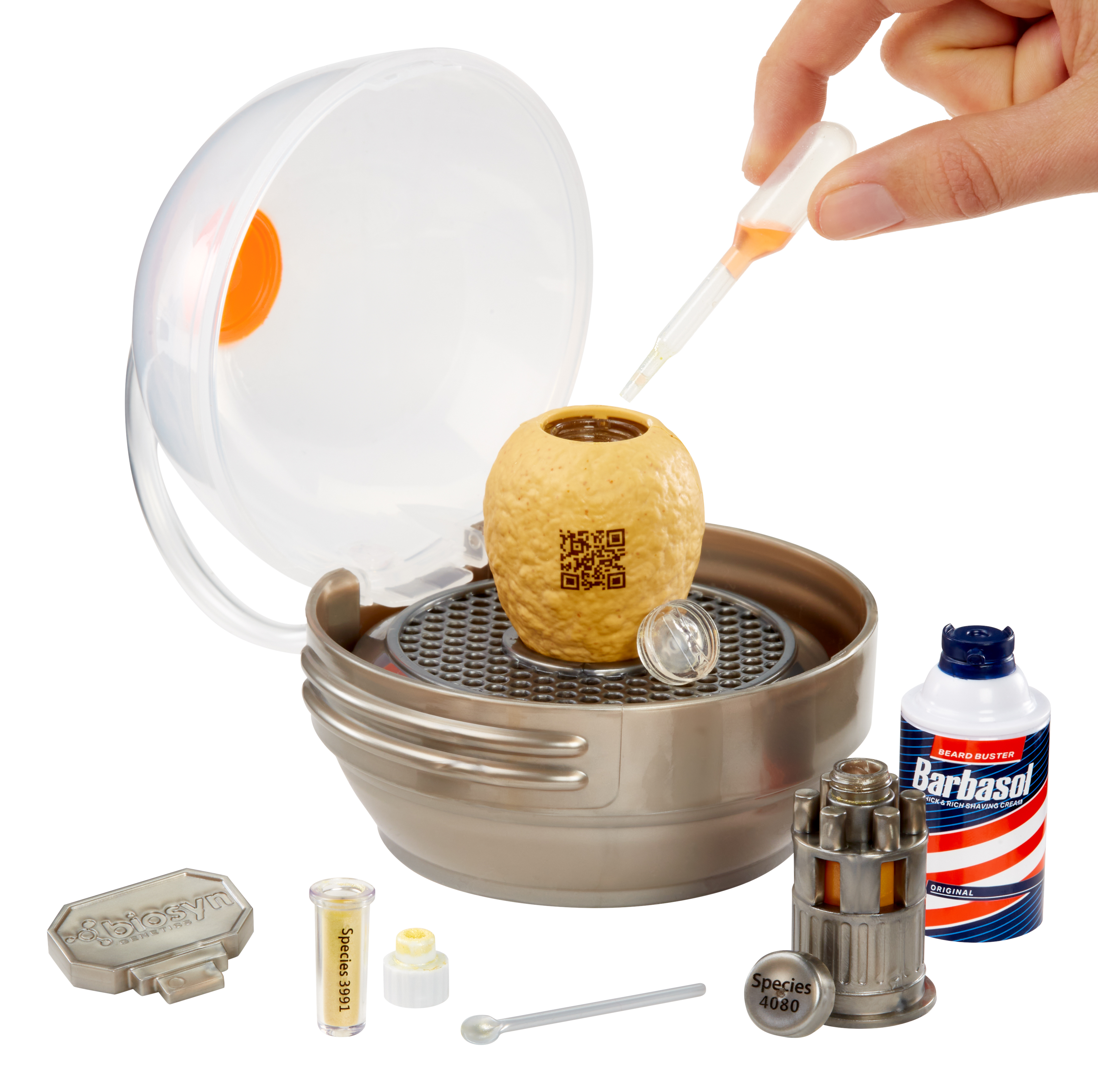 Ręka skrapla ciecz do brązowej kapsułki wewnątrz pojemnika. Otaczają ją różne narzędzia laboratoryjne i puszka Barbasol.