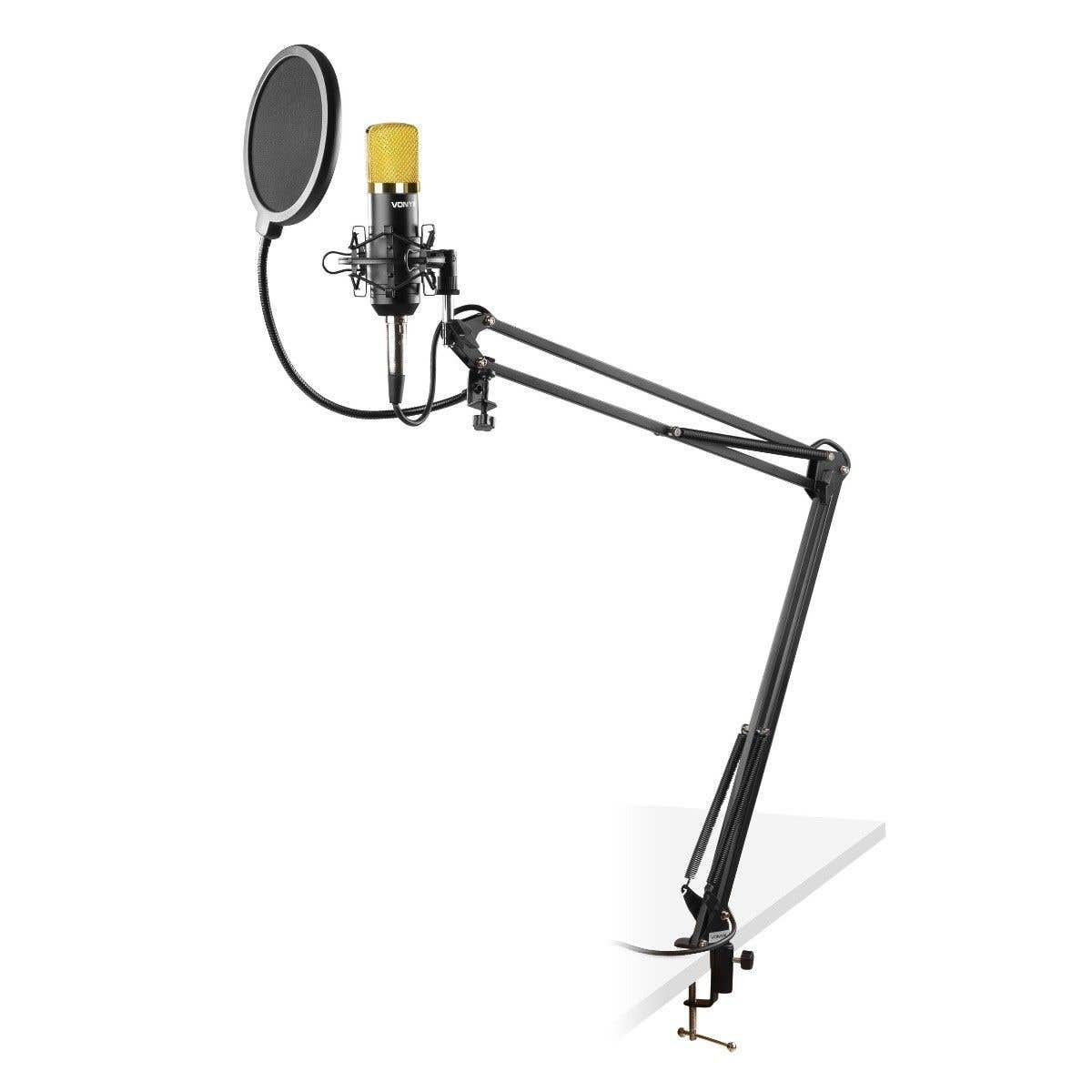 A studio microphone with a gold-colored head, pop filter, and adjustable arm. It's mounted on a white surface.