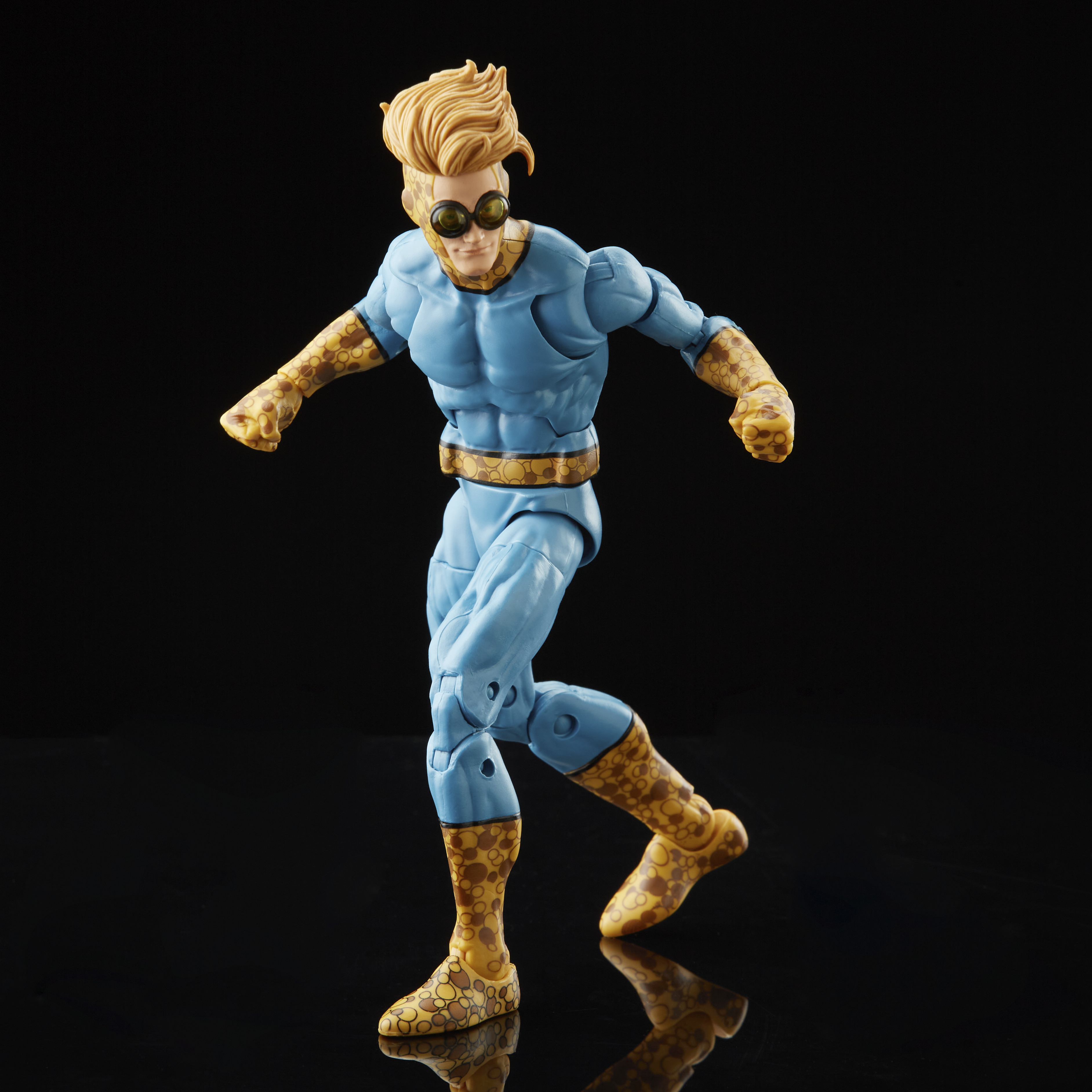 Figura de acción de superhéroe azul y amarillo, con gafas, sobre fondo negro. En pose de carrera.