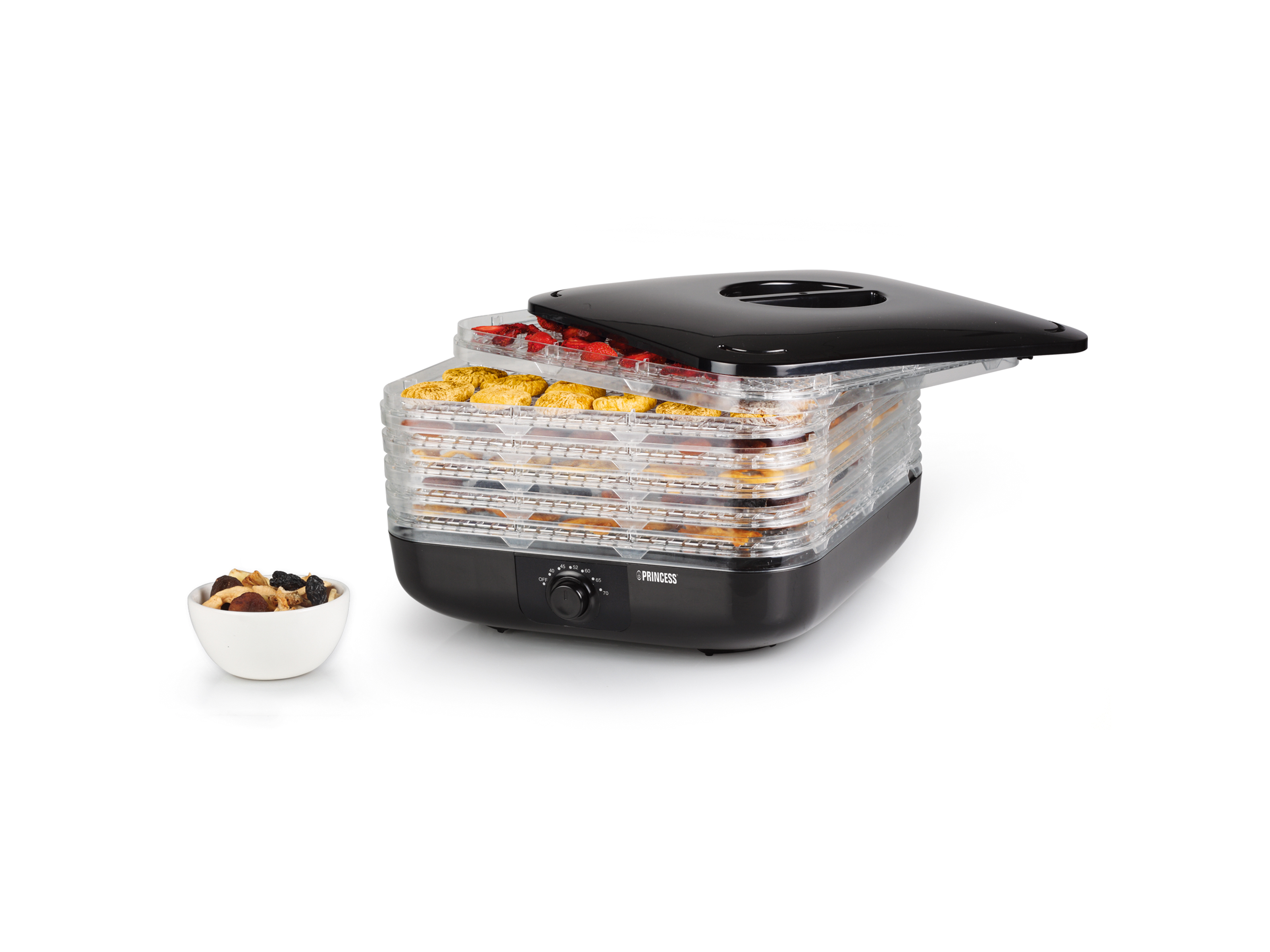 Suszarka do żywności z tacami z jedzeniem. Miska z suszonymi owocami po lewej. Czarna pokrywa otwarta.