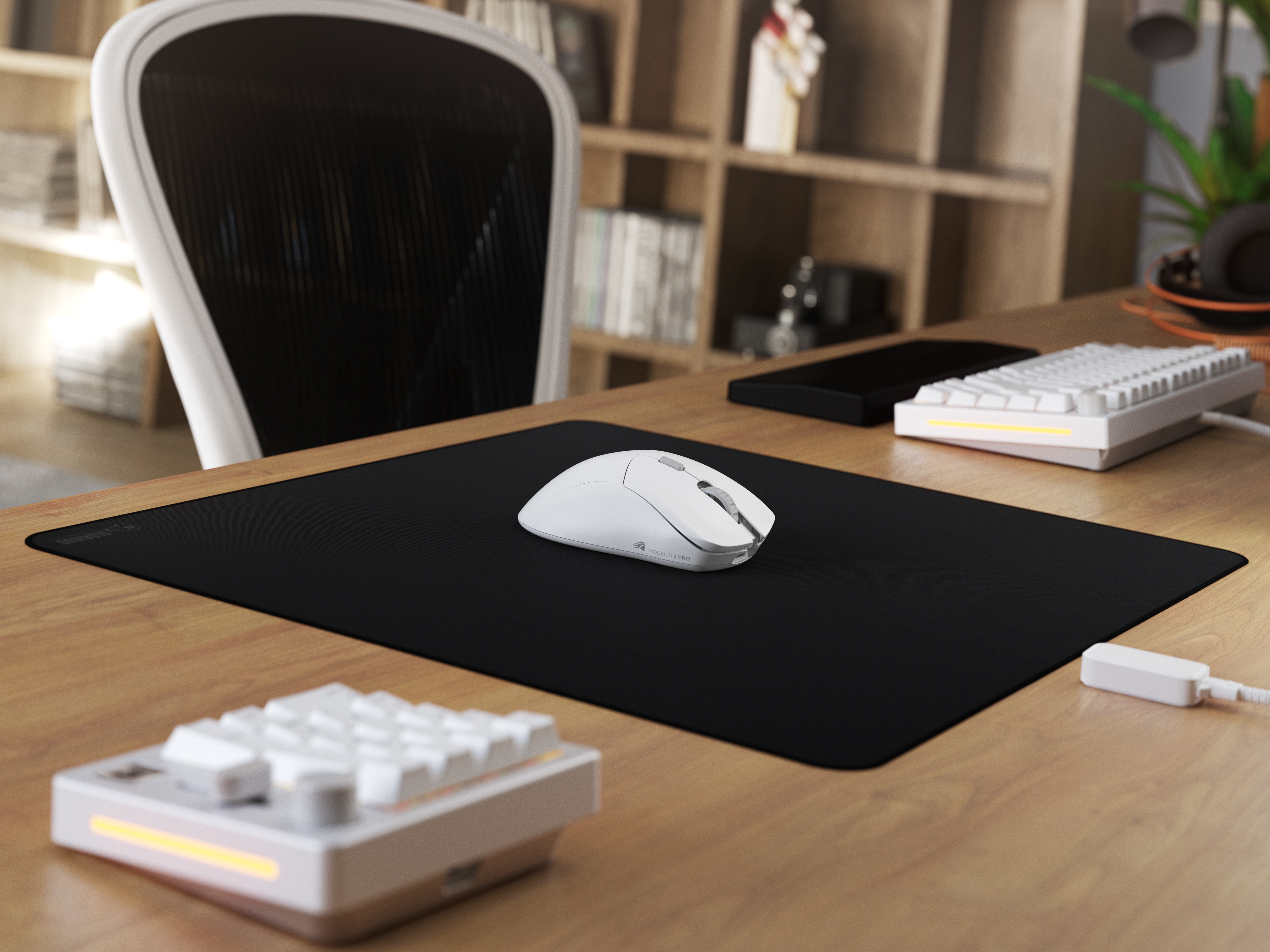 Ustawienia biurka z białą myszą, klawiaturą i czarną podkładką. Drewniane biurko, krzesło i regał w tle.