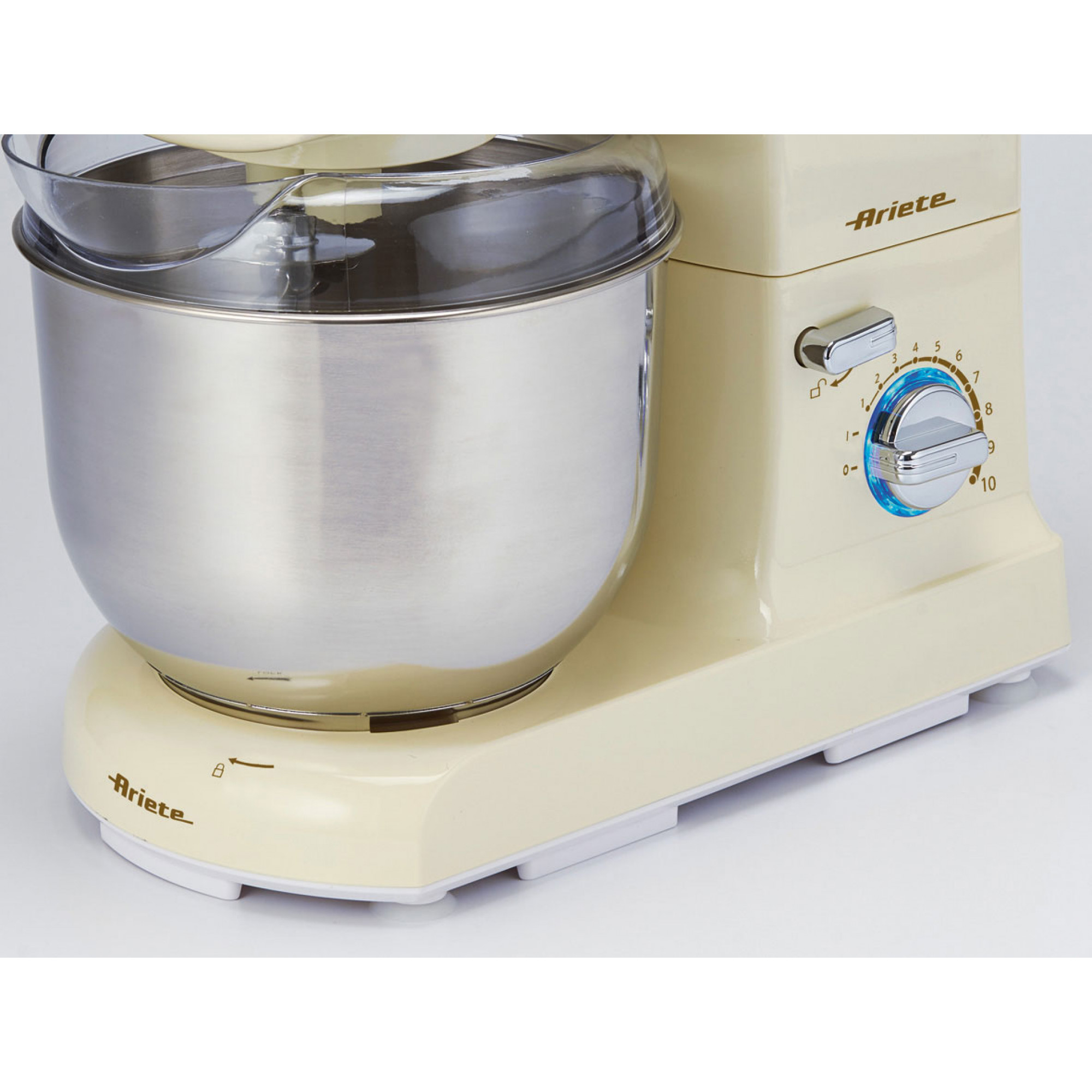 Una batidora de pie Ariete de color crema. Tiene un cuenco de acero inoxidable con una cubierta de plástico transparente. Tiene ajustes de velocidad.