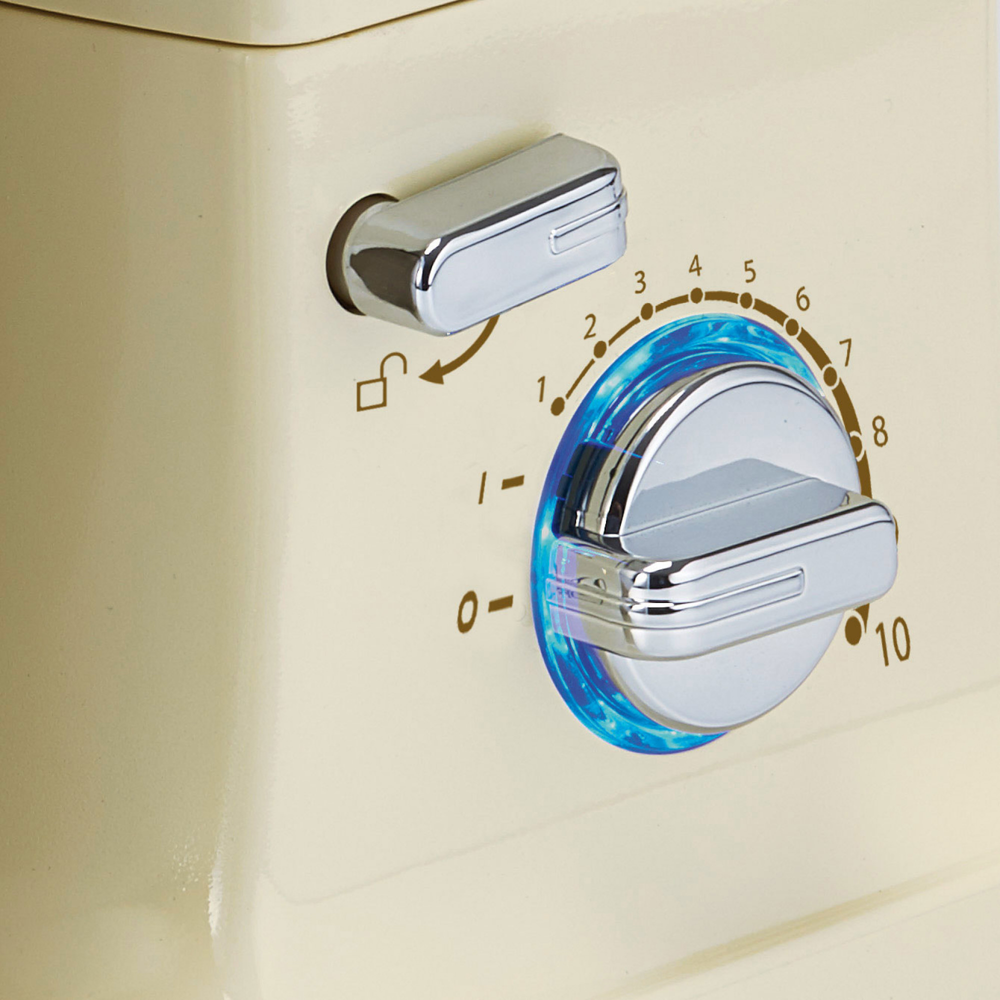 Primer plano de un electrodoméstico color crema con detalles cromados. Un dial tiene números y un símbolo de candado, el dial está en 10.