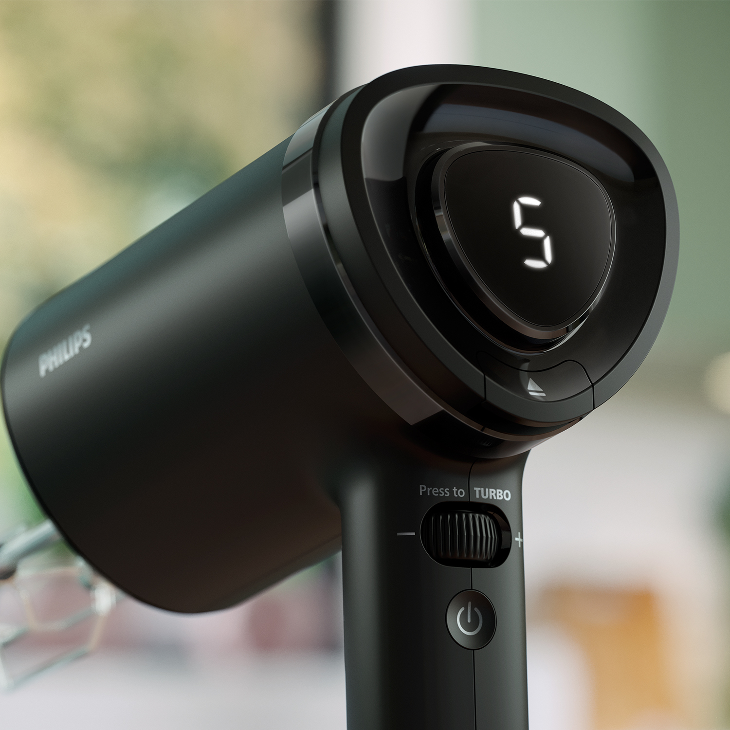 Czarny mikser ręczny Philips wyświetla na ekranie cyfrę '5'. Posiada przycisk turbo i przycisk zasilania. Tło jest rozmyte.