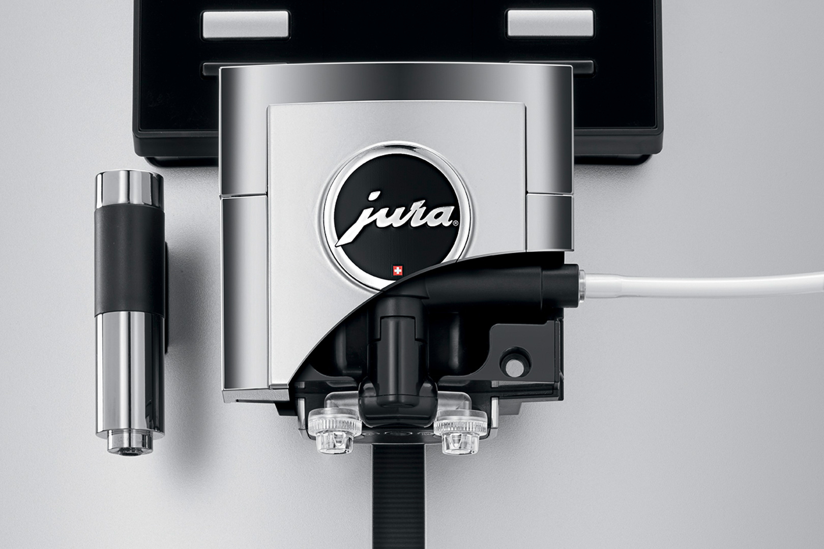 Nahaufnahme einer Jura-Kaffeemaschinenkomponente. Silberne und schwarze Elemente mit dem Jura-Logo. Ein weißes Rohr erstreckt sich von der Maschine.