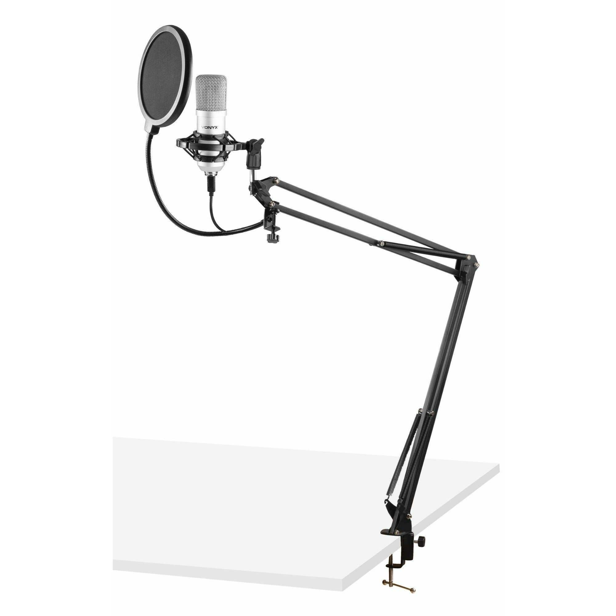 A microphone with a pop filter is mounted on an adjustable black arm, clamped to a white table.