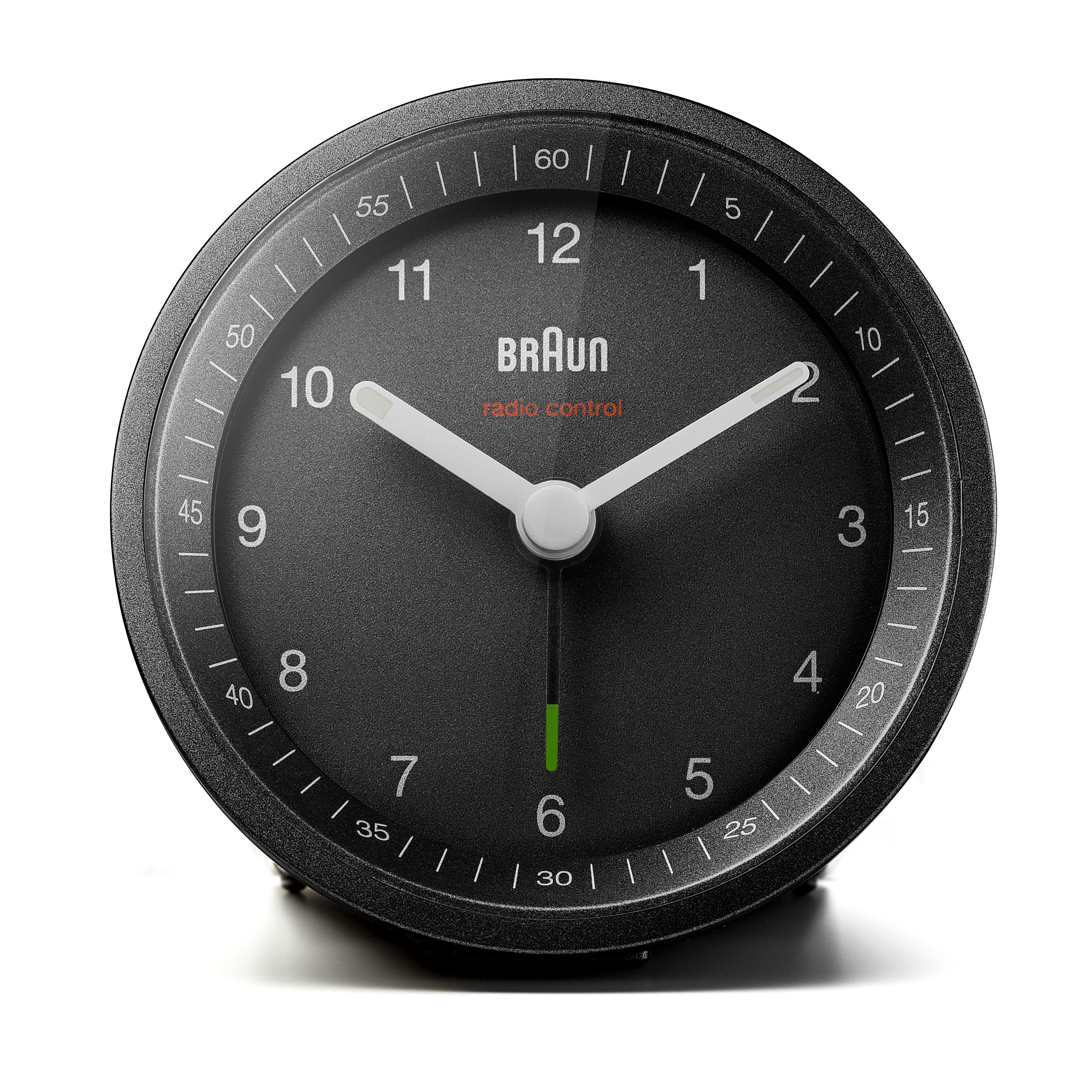 Une horloge Braun noire à contrôle radio. Aiguilles et chiffres blancs sur un cadran gris foncé. L'horloge est sur une surface blanche.