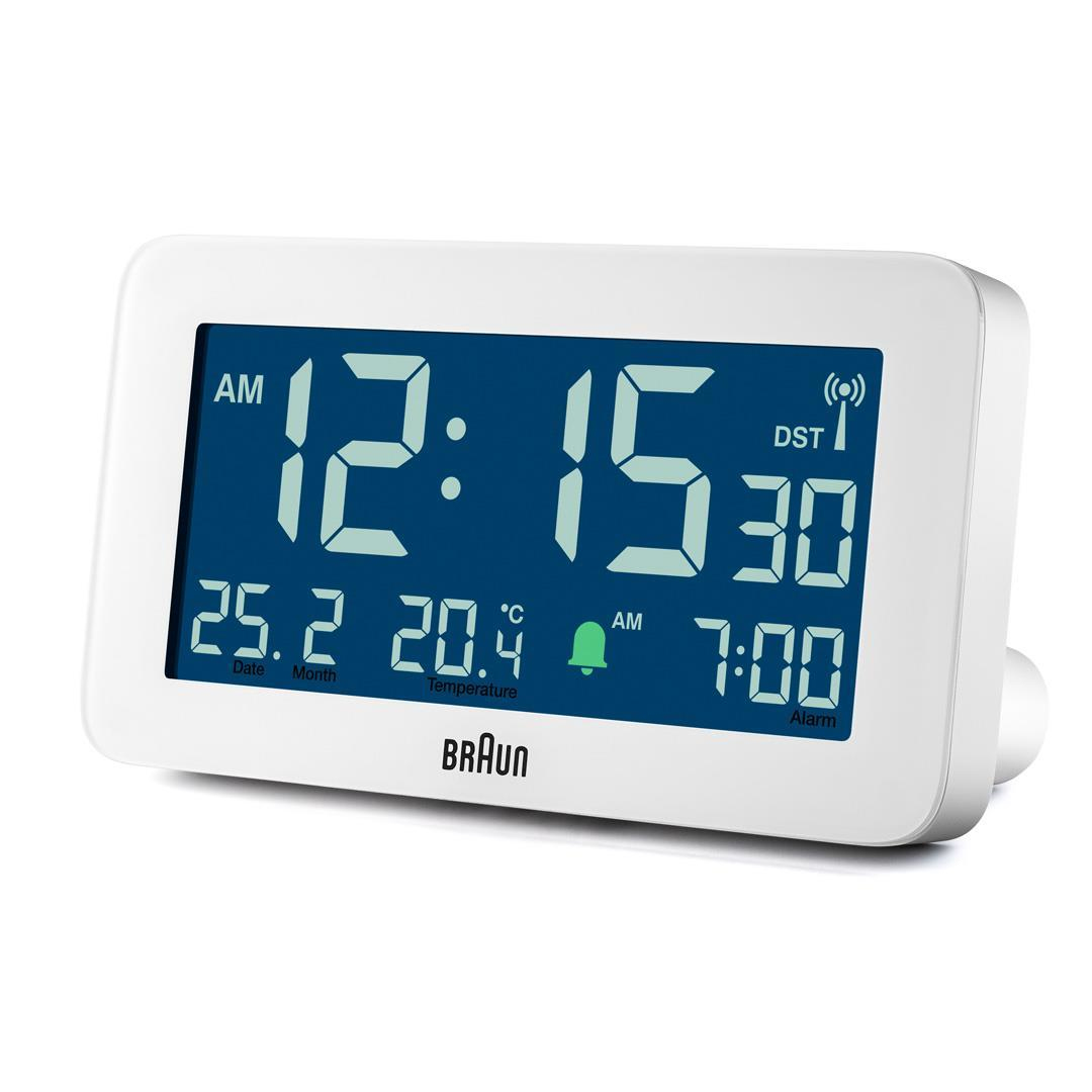 Eine weiße digitale Braun-Uhr zeigt 12:15:30 AM, Datum, Monat, Temperatur und Wecker auf 7:00 AM an. Sie hat einen blauen Bildschirm.