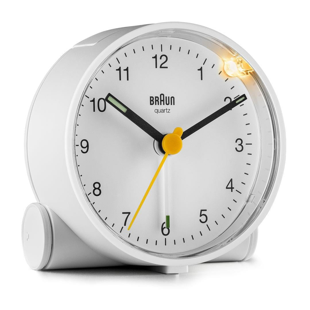 Ein weißer Braun-Quarz-Wecker mit schwarzen Zeigern und einem gelben Sekundenzeiger. Die Zeit ist ungefähr 10:09 Uhr.