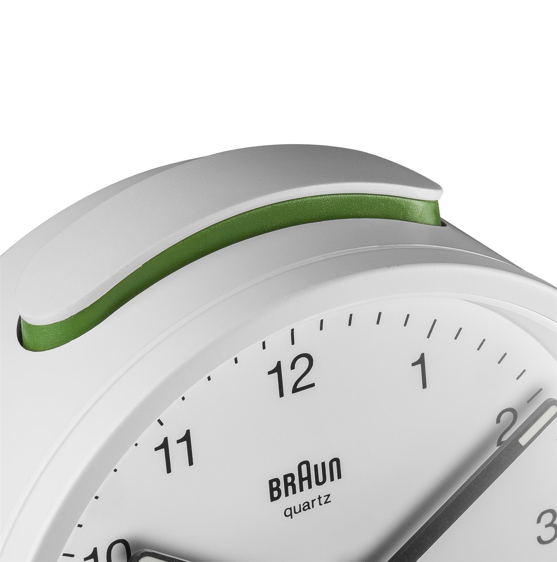 Nahaufnahme einer weißen Braun-Quarzuhr mit grünem Akzent. Die Uhr zeigt die Uhrzeit an, wobei die Zahl 12 sichtbar ist.