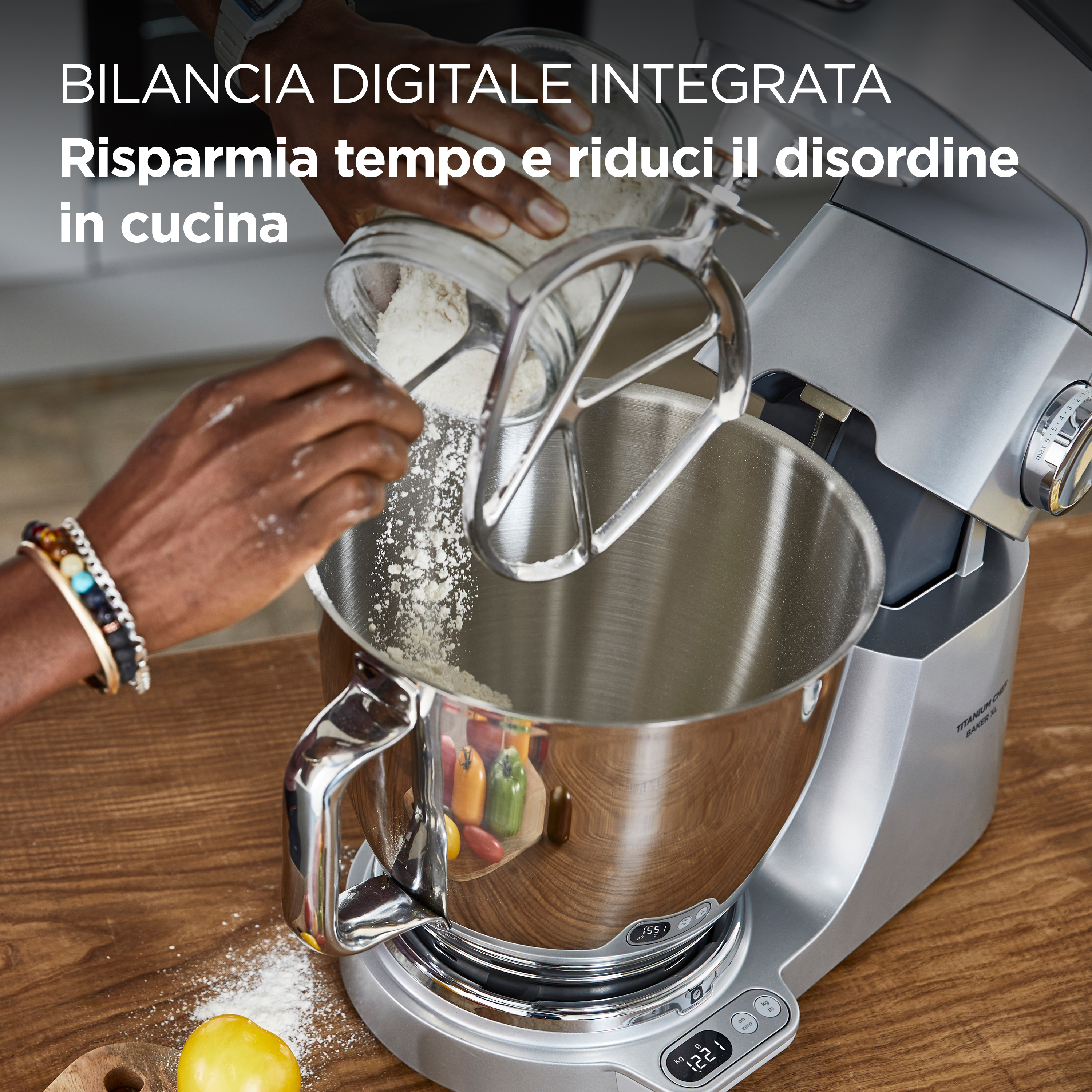 Osoba wsypuje mąkę do srebrnej miski miksera kuchennego. Widoczny drewniany blat i tekst po włosku.