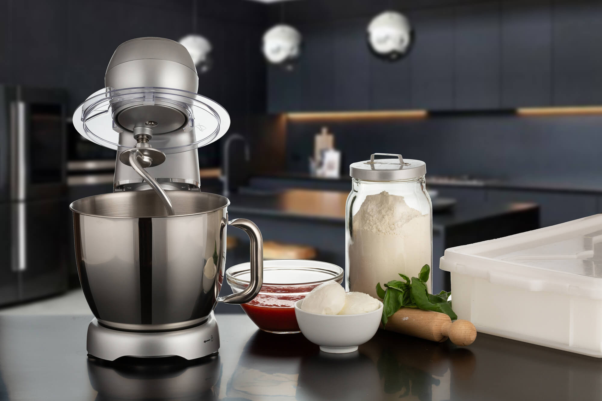 Eine Küchenszene mit Mixer, Zutaten wie Mehl, Mozzarella und Sauce. Es ist vor einem verschwommenen Küchenhintergrund aufgebaut.