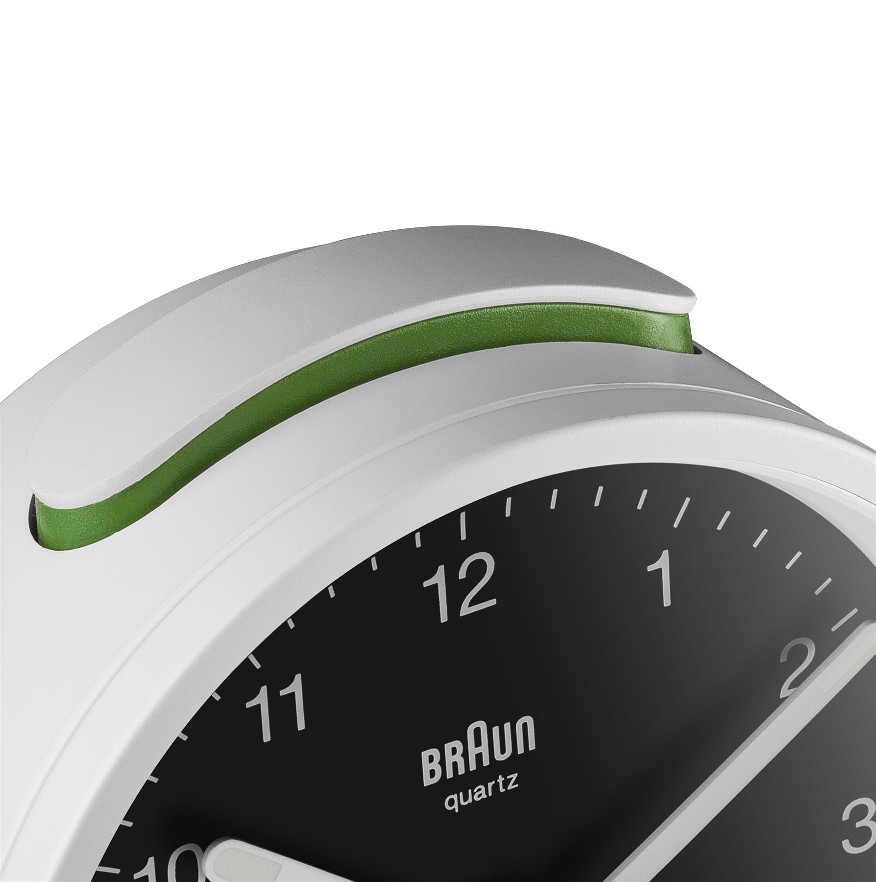 Gros plan d'un réveil Braun blanc et vert. Le cadran est noir avec des chiffres blancs. Le dessus a un accent vert.
