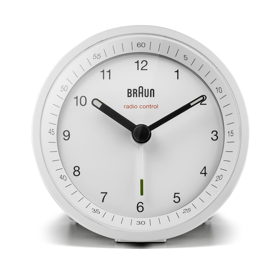 Un réveil Braun blanc radio-piloté. Les aiguilles noires indiquent l'heure. Les chiffres et les marques sont noirs. La marque est visible.