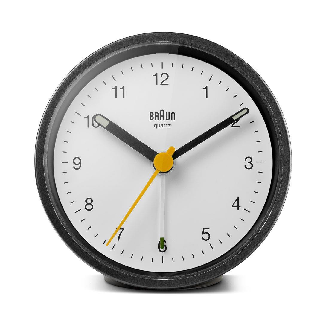 Horloge quartz Braun ronde. Cadre noir, cadran blanc, aiguilles noires et trotteuse jaune. L'heure est environ 1:50.
