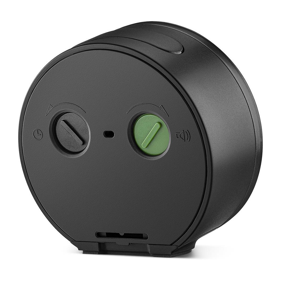 Un appareil noir arrondi avec deux cadrans, un noir et un vert. Il a un symbole de haut-parleur et une petite fente en bas.