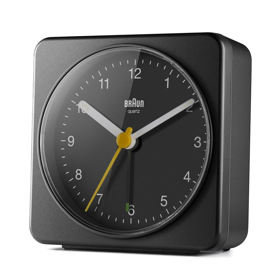Un reloj de cuarzo Braun negro. Tiene una esfera negra con manecillas y números blancos y amarillos. El reloj es cuadrado.