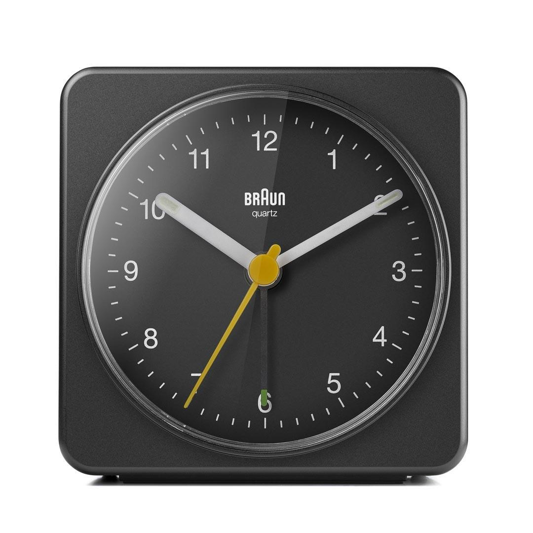 Despertador Braun cuarzo negro. Agujas blancas, segundero amarillo. Números y marcas en la esfera negra. Forma rectangular.