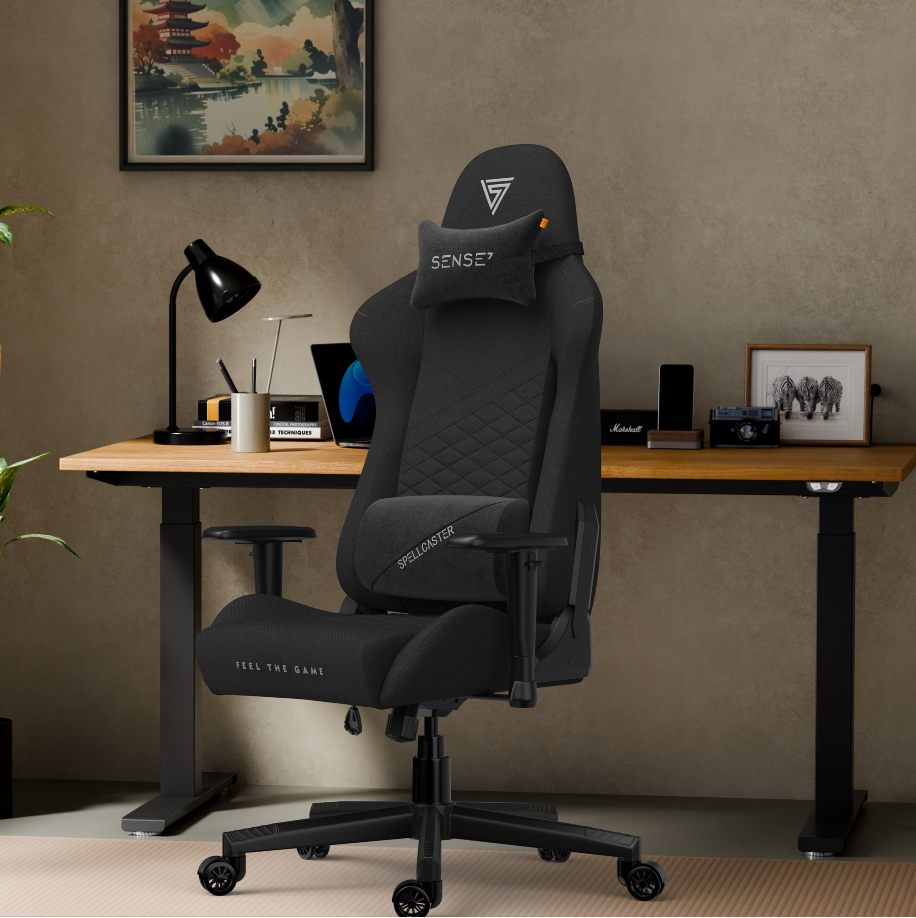 Een zwarte gamestoel met een logo staat in een kamer. Een houten bureau heeft een laptop, een lamp en andere items. Er hangt een schilderij.