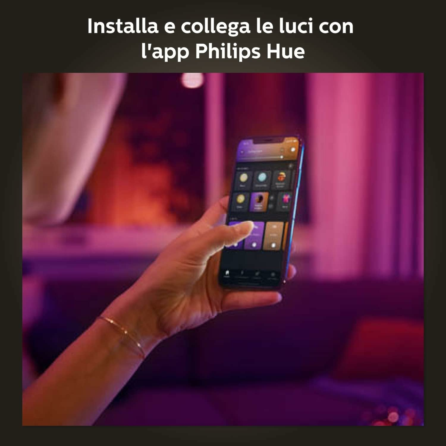 Eine Hand hält ein Telefon, auf dem die Philips Hue App angezeigt wird. Der Hintergrund ist ein verschwommenes Wohnzimmer mit Lila- und Rottönen.
