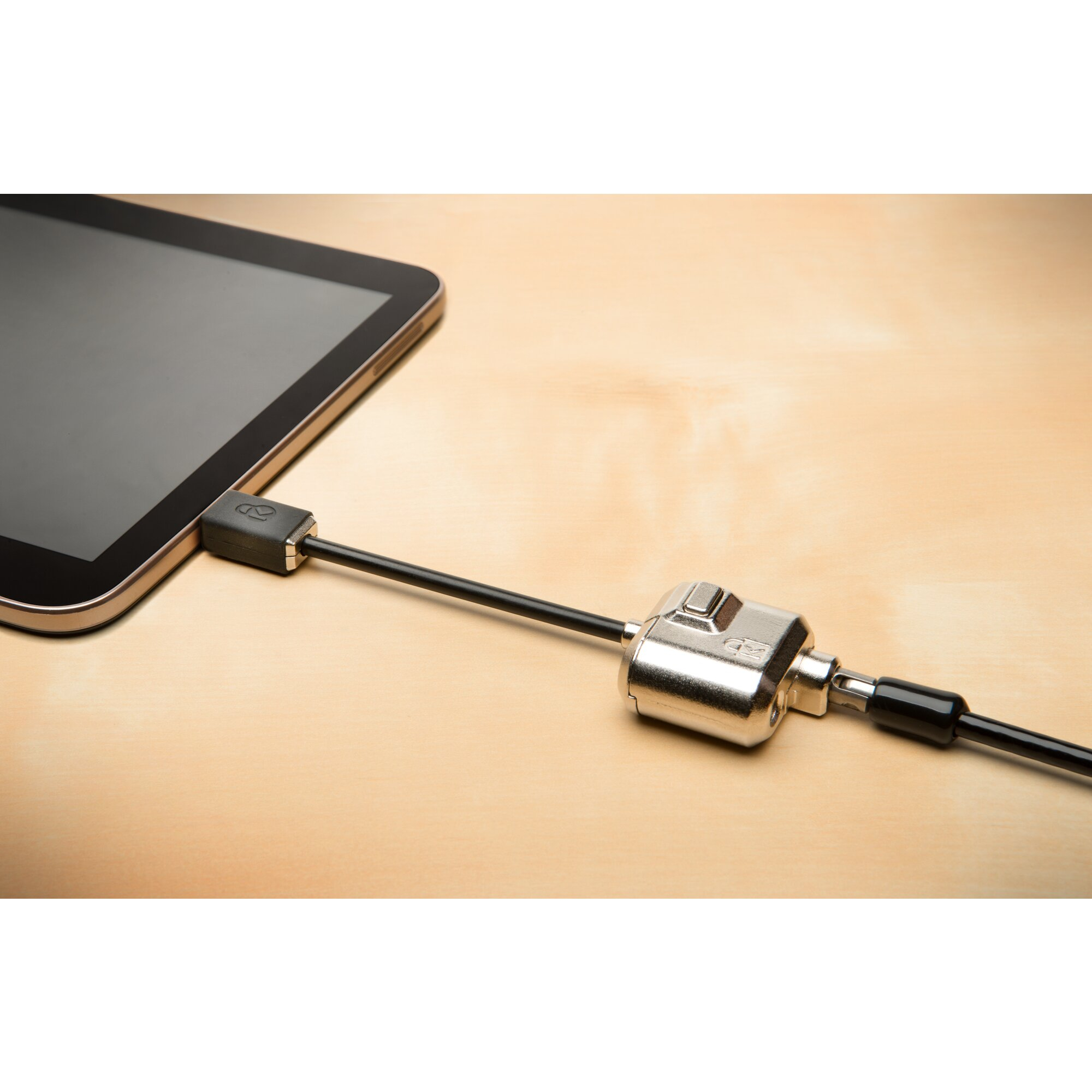 Tablet mit Kabelschloss gesichert. Das Tablet liegt auf einer hellen Holzoberfläche. Das Kabelschloss ist silber und schwarz.