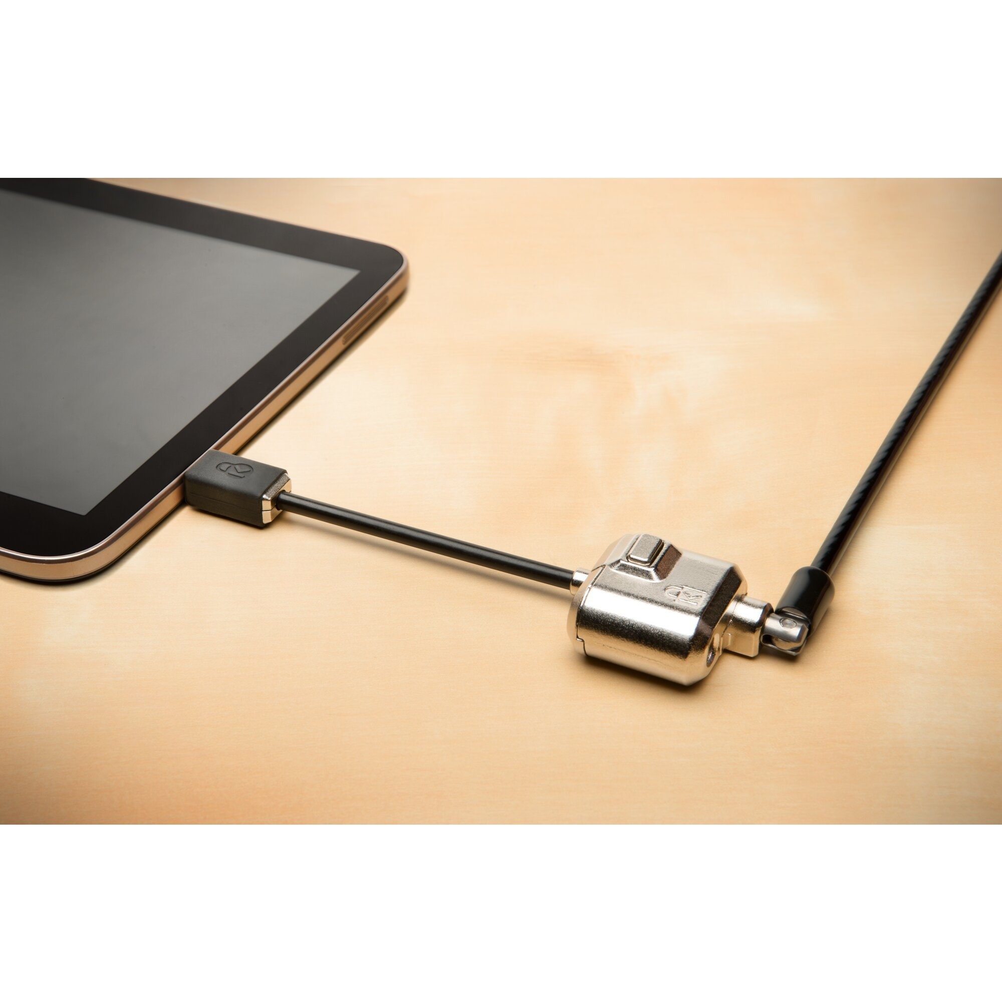 Ein Tablet, das mit einem silbernen Schloss und Kabel auf einer hellbraunen Holzoberfläche gesichert ist. Das Kabel ist am Tablet befestigt.