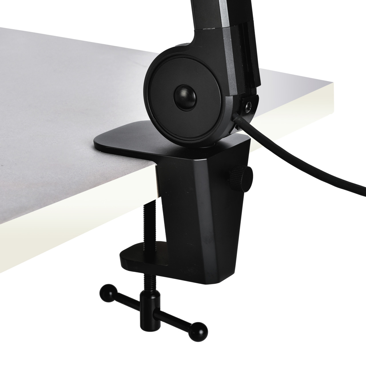 Une pince de bureau noire est fixée à un bureau gris. Un câble noir est connecté à la pince. La pince a un bouton et une vis.
