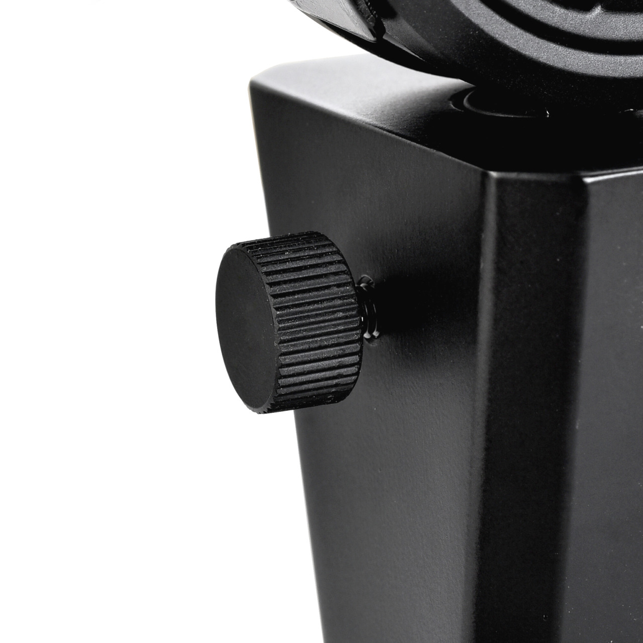 Gros plan d'un objet noir avec un bouton rond et strié. L'objet a une base carrée. Fond blanc.