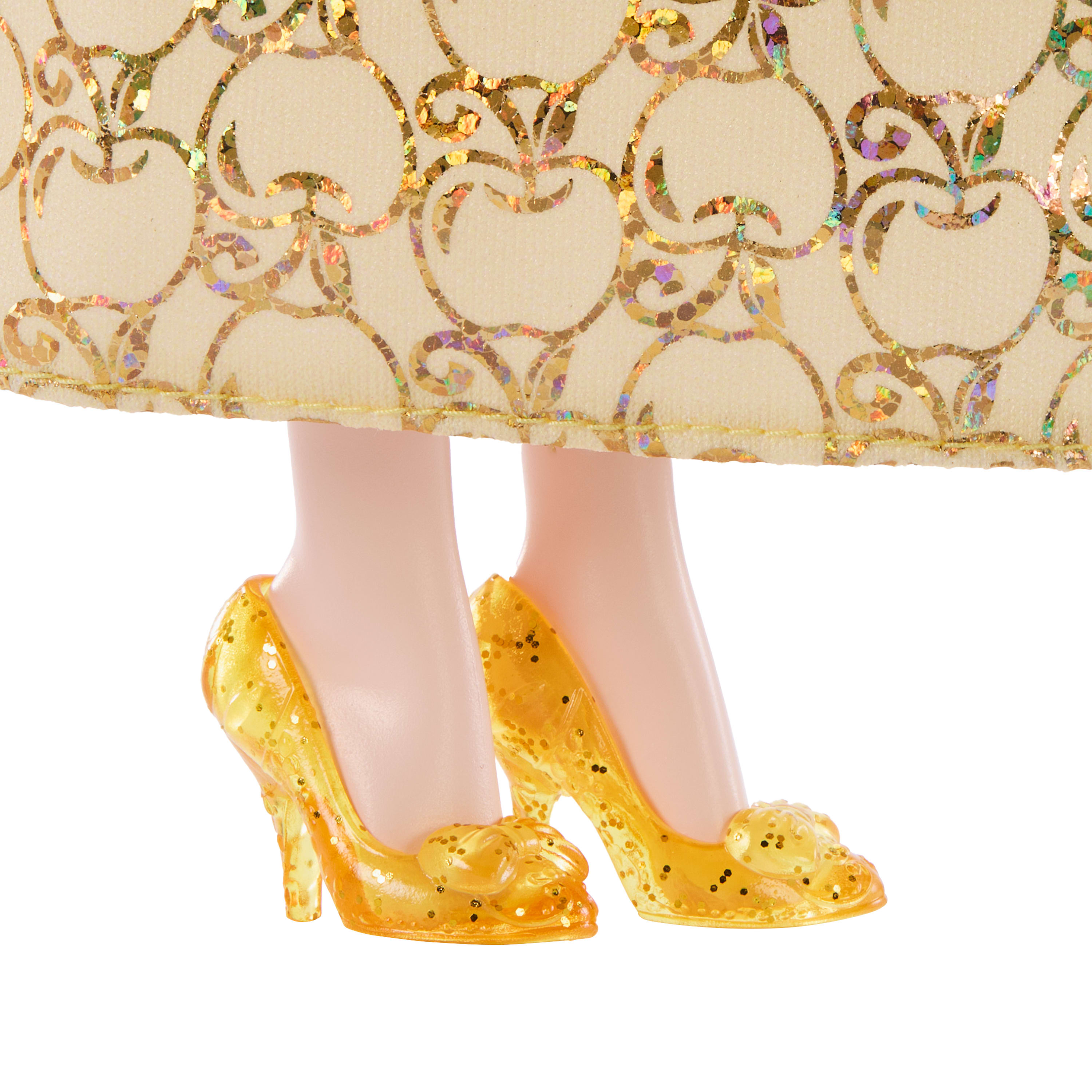 Stopy lalki w żółtych szpilkach. Sukienka jest kremowa ze złotymi wzorami kwiatowymi. Białe tło.