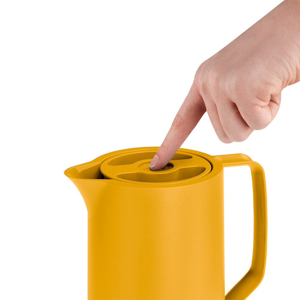 Eine Hand drückt auf den Deckel eines gelben Krugs. Der Krug steht vor weißem Hintergrund. Der Finger drückt auf den Deckel.