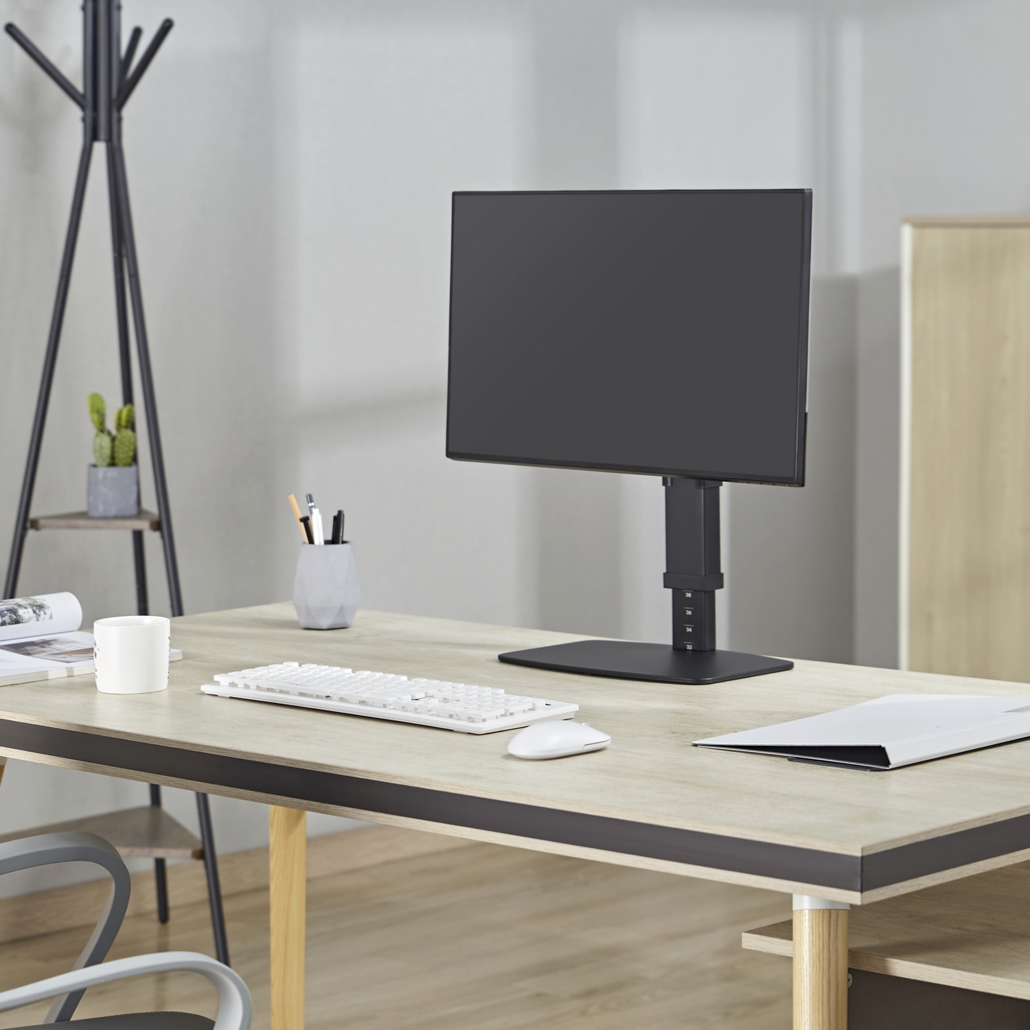 Un escritorio de oficina moderno con un monitor de computadora, teclado, mouse y otros artículos de papelería. El escritorio es de madera clara.