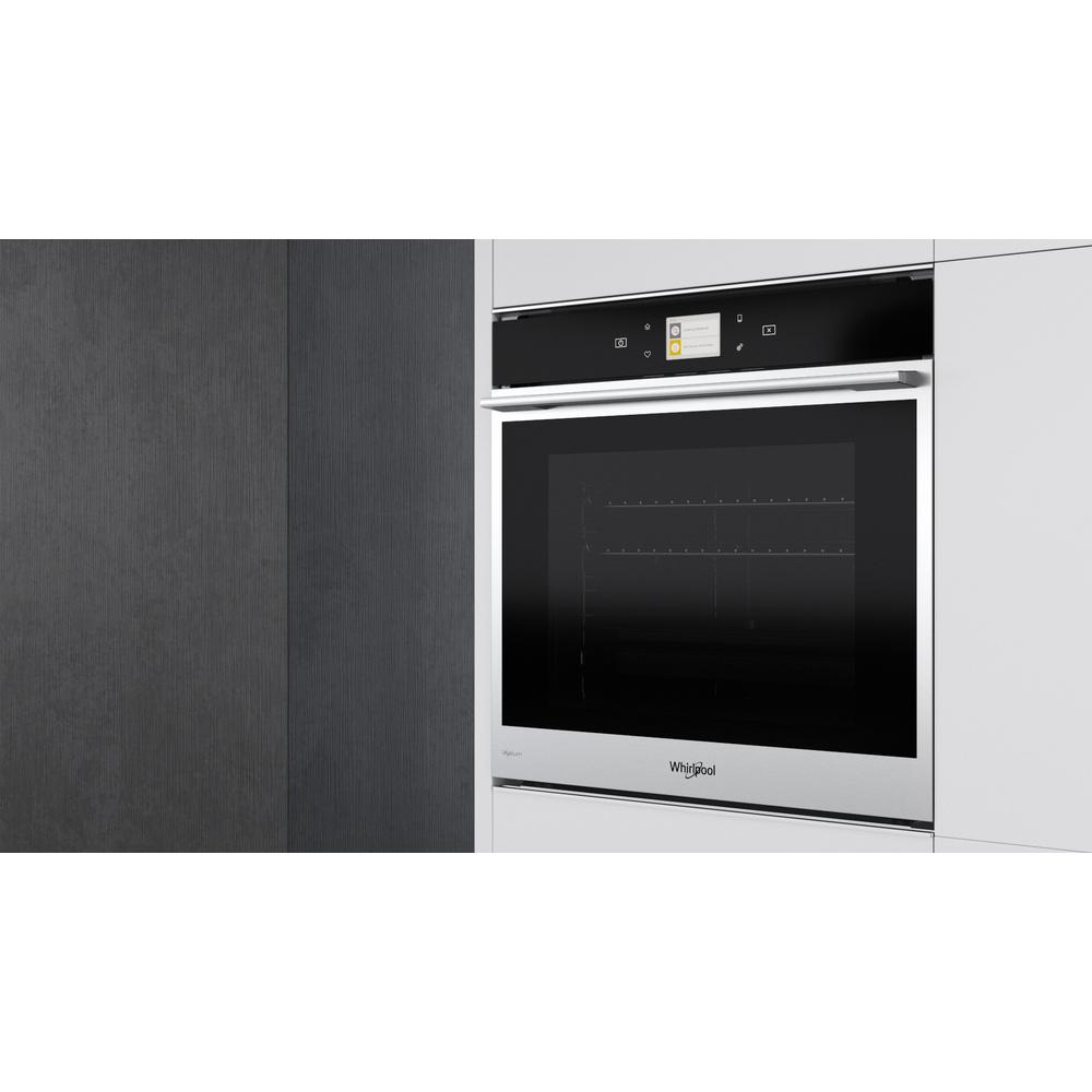 Un moderno horno Whirlpool integrado en un armario de cocina blanco. El horno tiene una puerta de cristal negra.