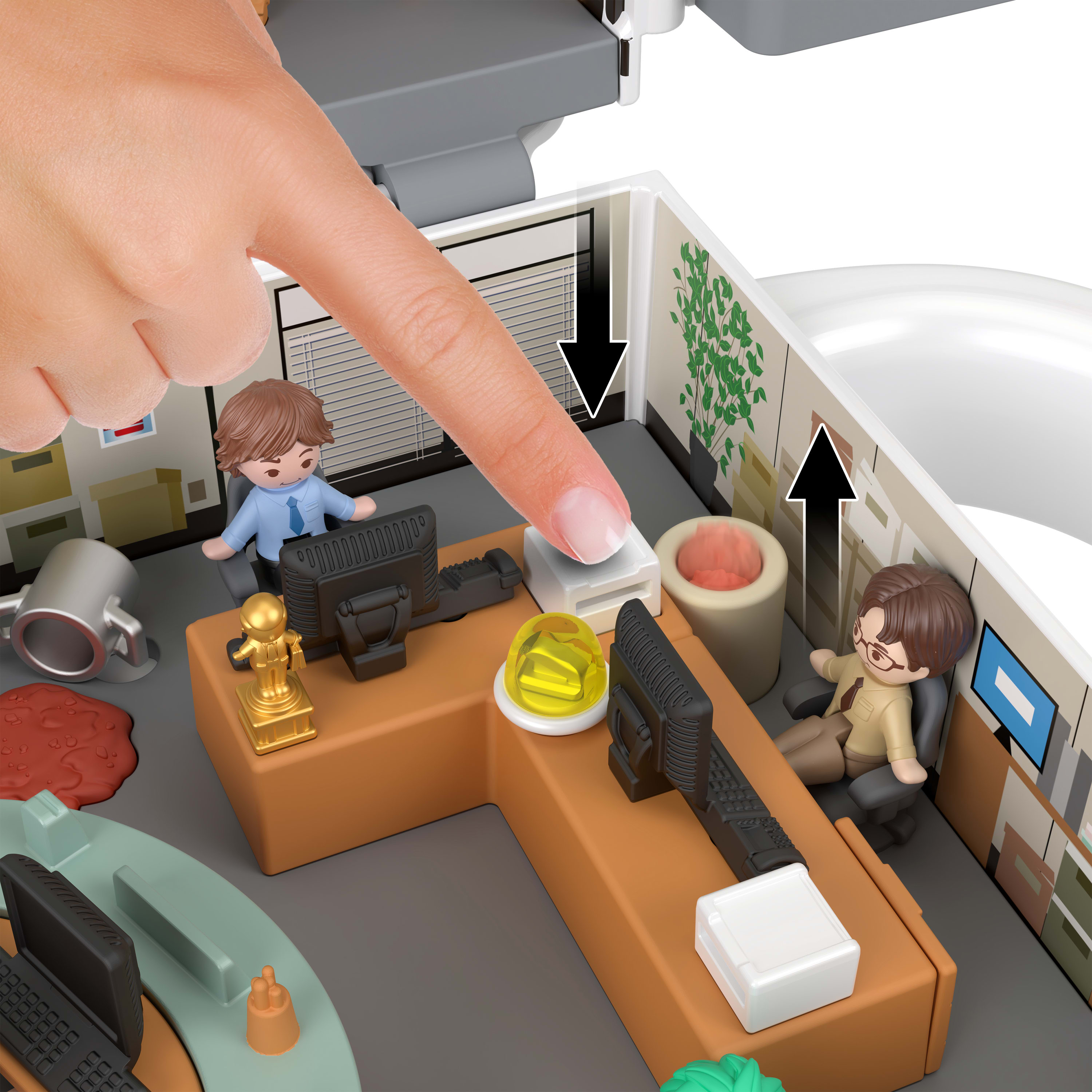 Palec naciska przycisk na zabawce biurowej. W scenie znajdują się figurki pracowników biurowych. Na biurku stoi trofeum.