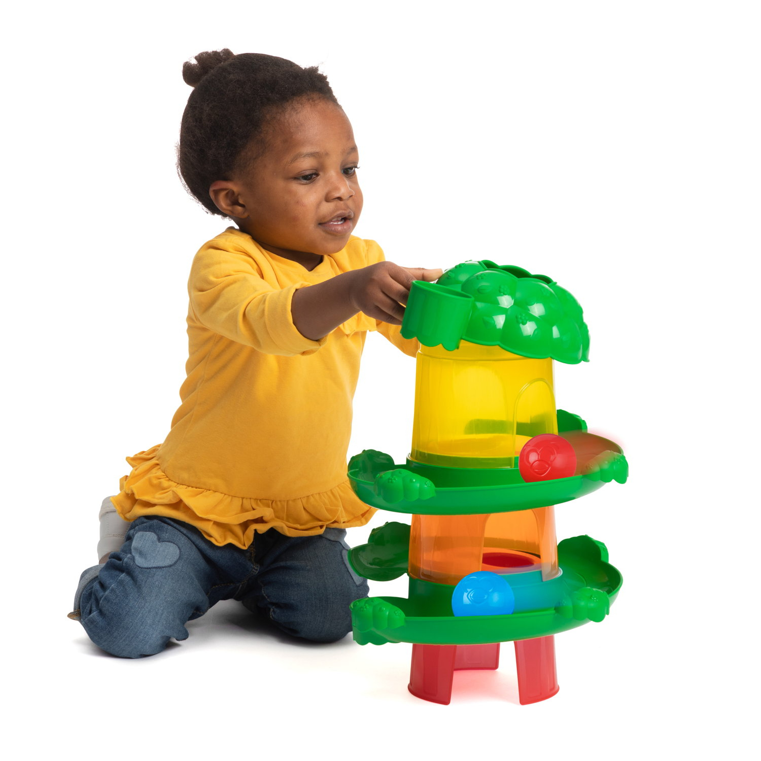 Dziecko w żółtej koszuli i dżinsach bawi się zabawką. Zabawka to wieża z kolorowymi kulkami.