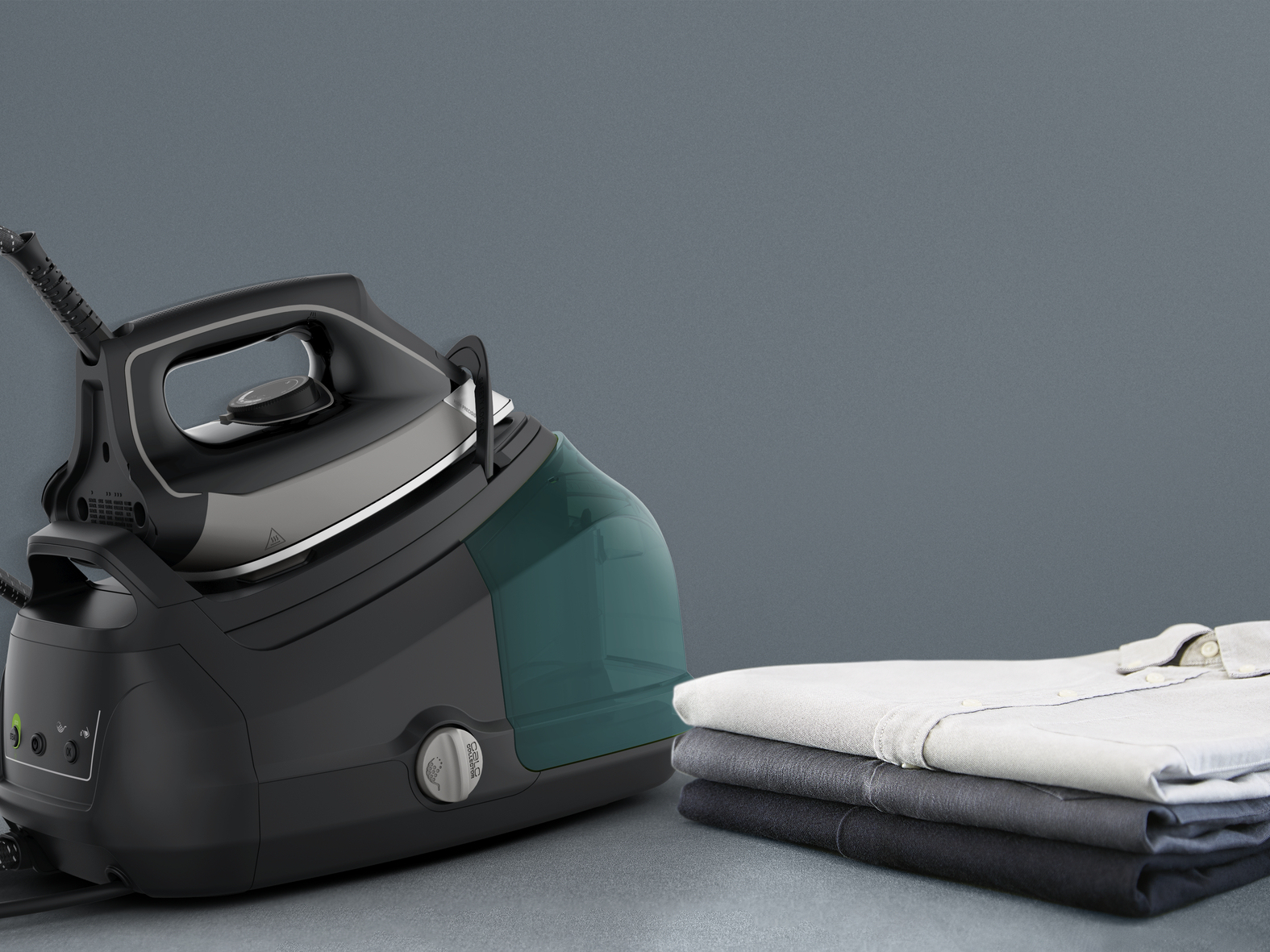 Una plancha de vapor con base negra y depósito de agua verde junto a una pila de camisas dobladas, sobre fondo gris.