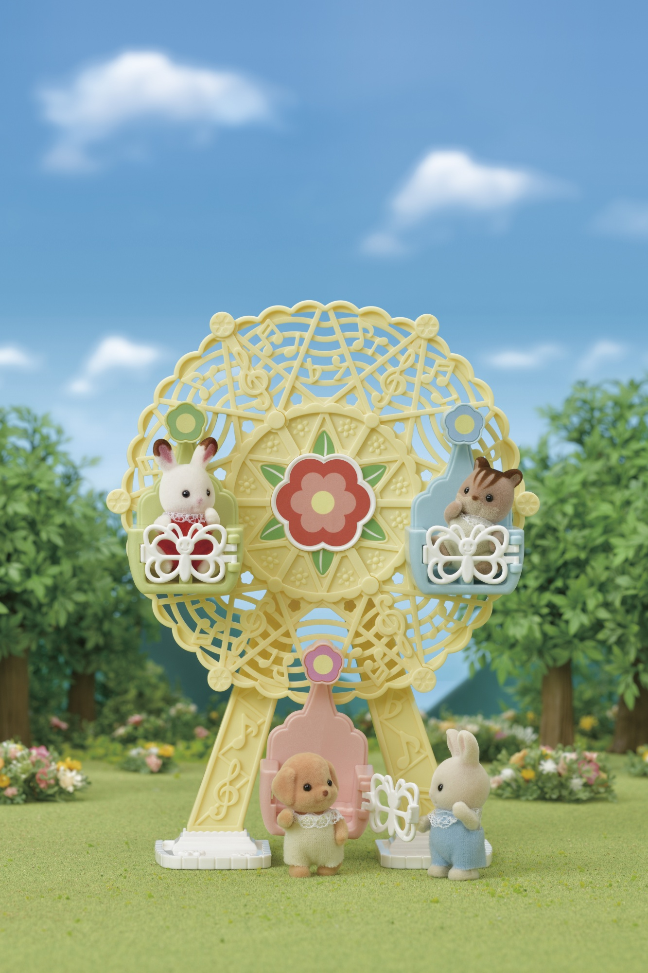 Zabawkowe diabelskie koło z figurkami zwierząt. Królik, wiewiórka i pies widoczne na zielonej trawie z drzewami i błękitnym niebem.