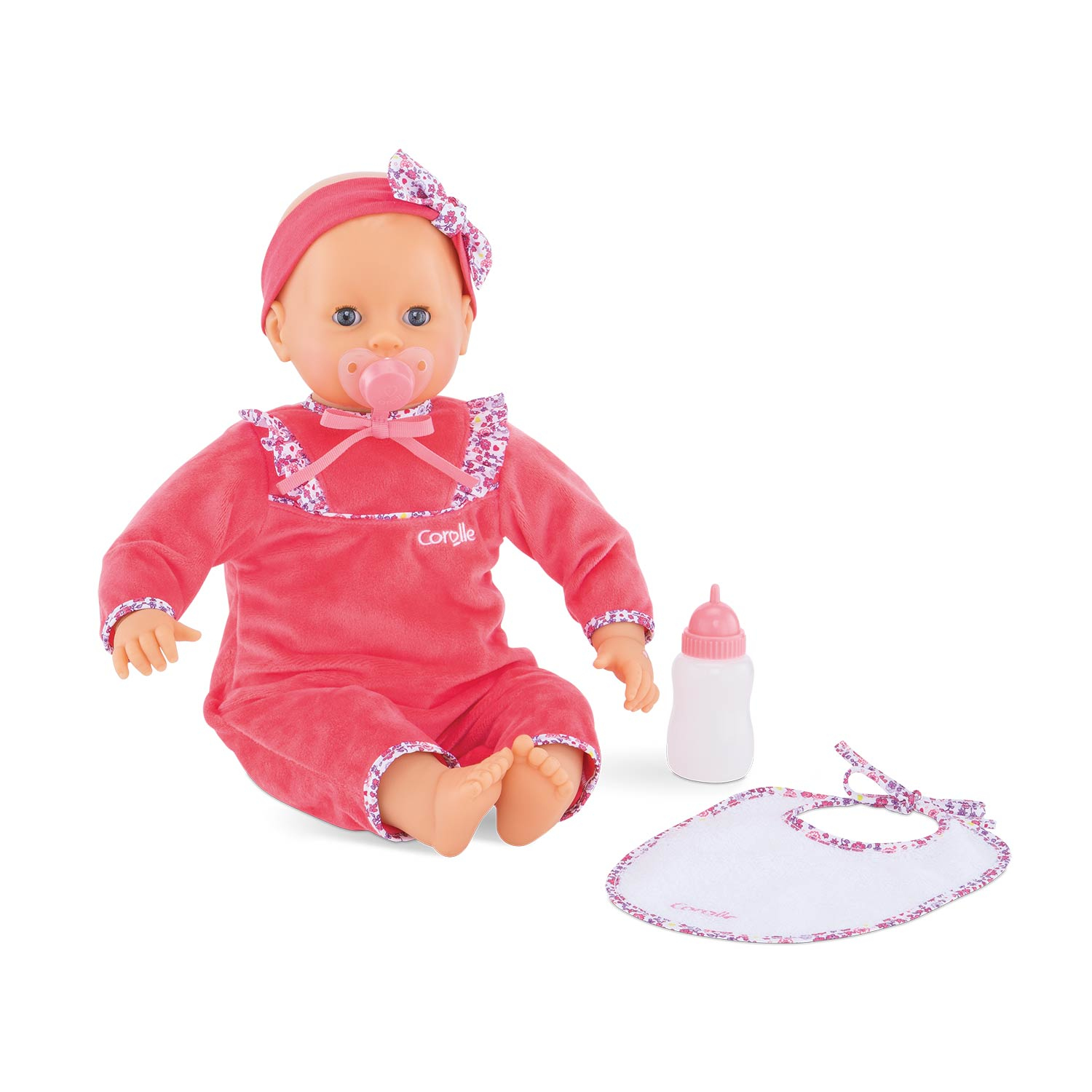 Eine Babypuppe in rosa Overall, Schnuller, Stirnband, Lätzchen und Flasche. Blumendetails auf Lätzchen und Stirnband. Auf weißem Hintergrund.
