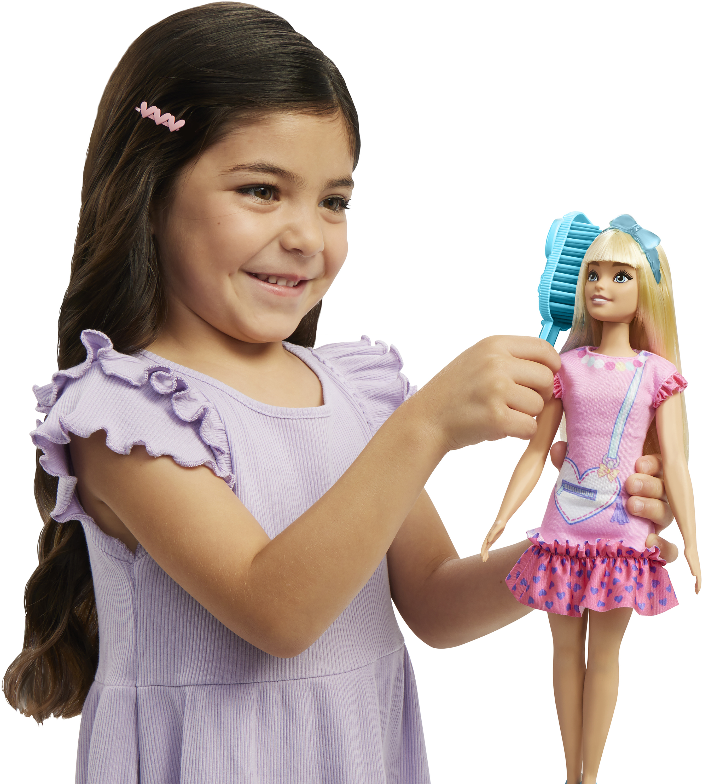 Ein Mädchen bürstet lächelnd die Haare einer Puppe. Die Puppe trägt rosa und blaue Kleidung.