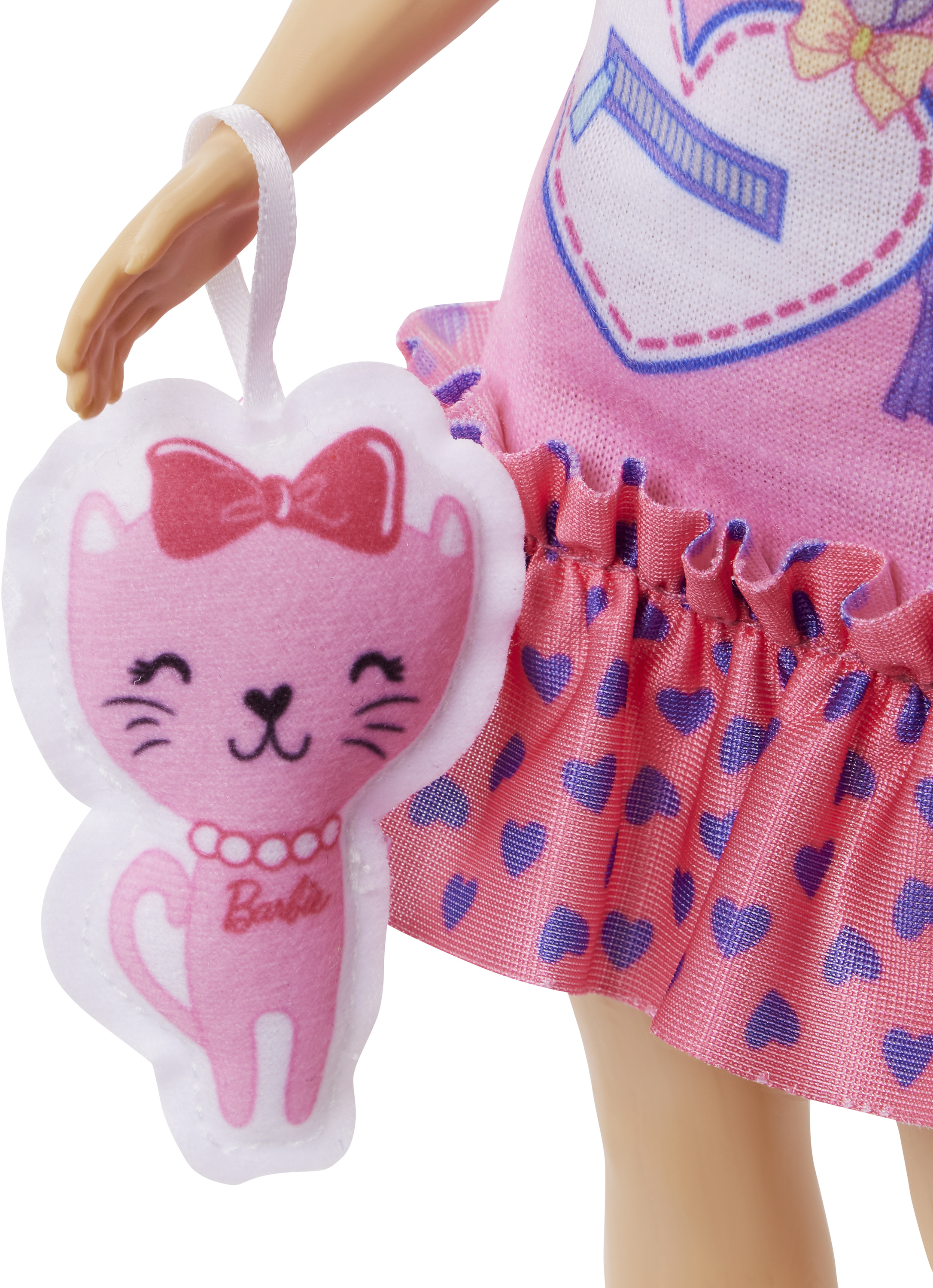 Eine Puppe hält eine rosa katzenförmige Geldbörse. Die Puppe trägt ein rosa Kleid mit Herzdetails.