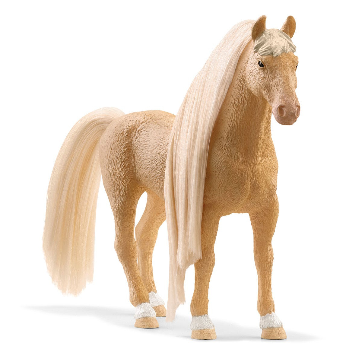 A palomino horse figurine stands on a white surface. It has a long, flowing white mane and tail, and white markings on its legs.