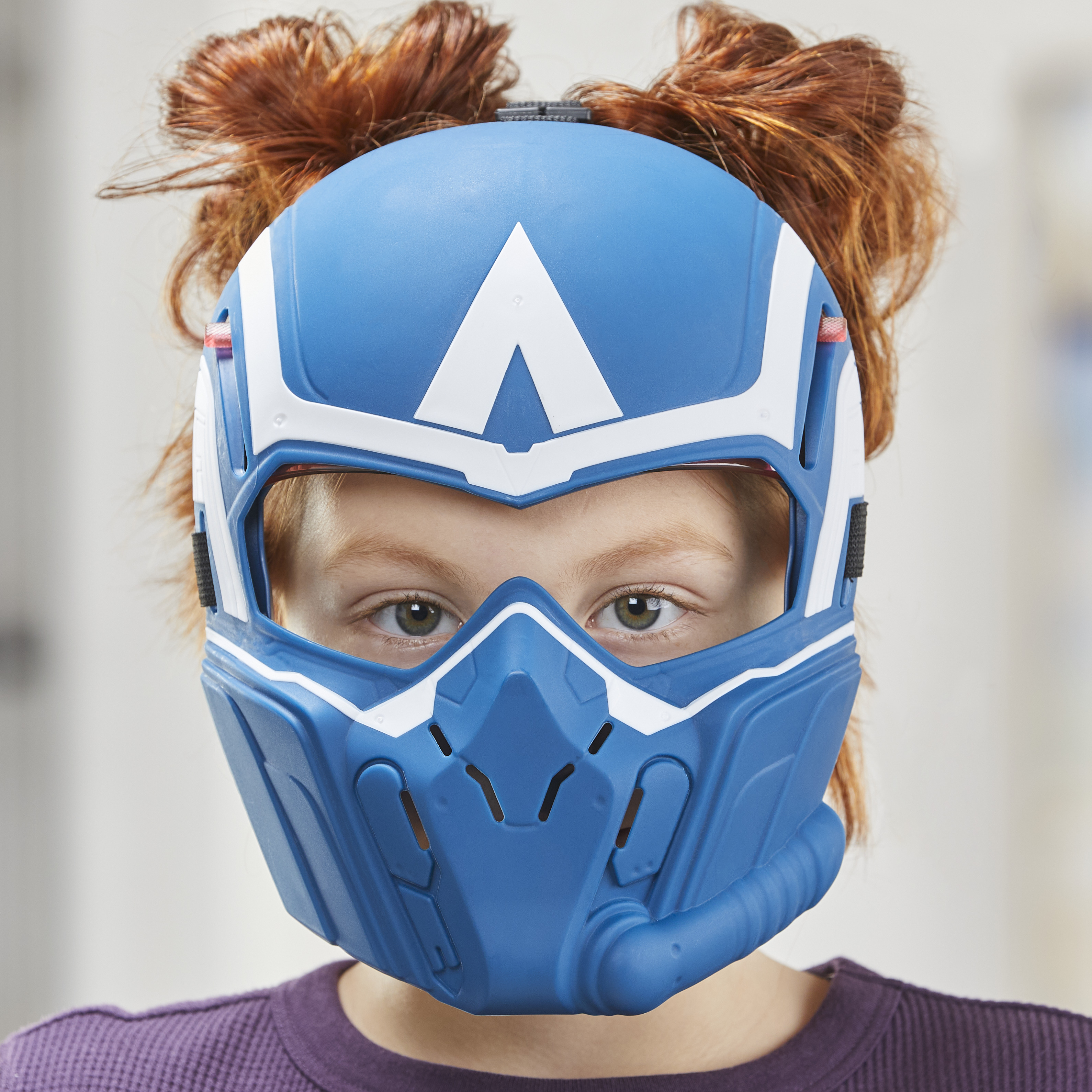Una persona con un casco azul y blanco del Capitán América y cabello rojo. La persona lleva una camisa morada.