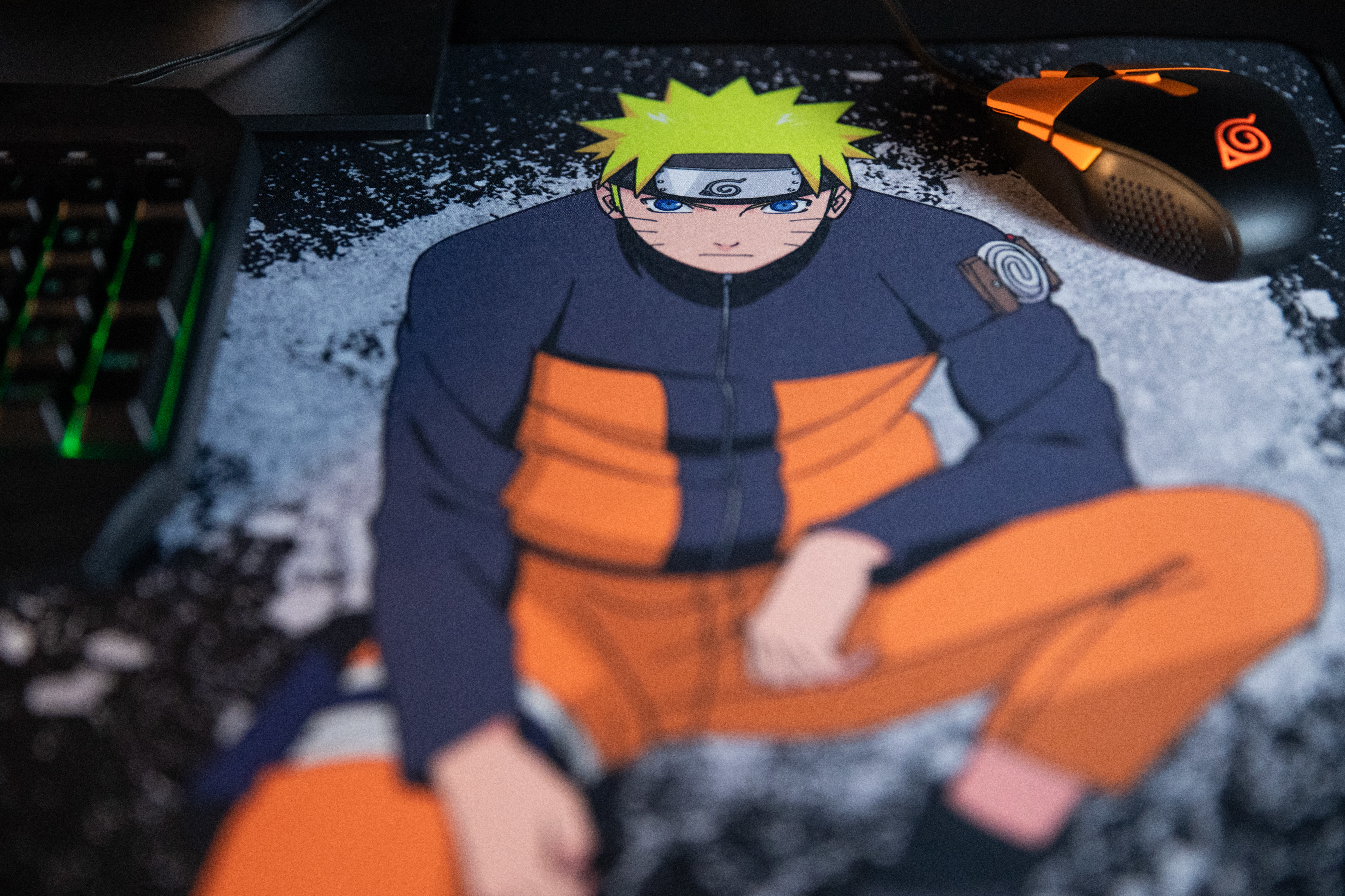 Naruto na podkładce pod mysz. Klawiatura i mysz są widoczne. Naruto w pomarańczowym i niebieskim stroju.