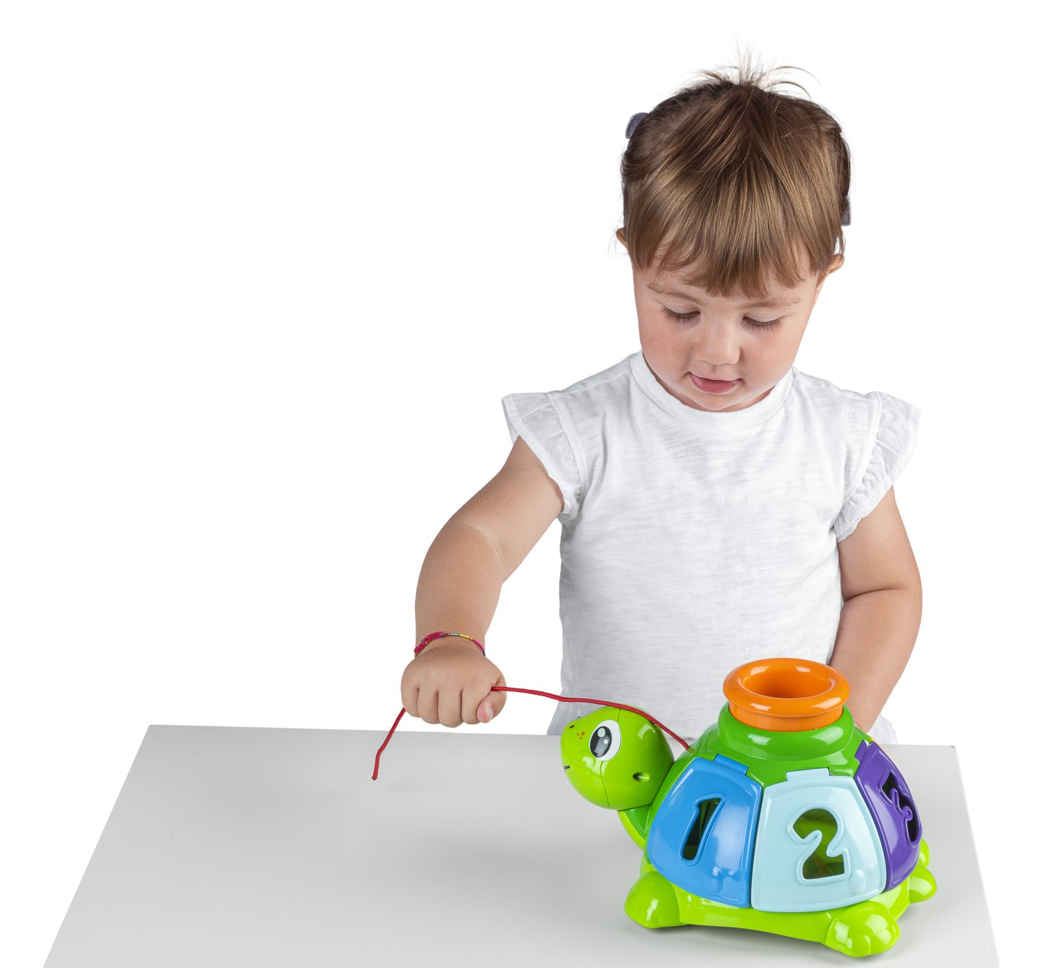 Una bambina guarda un colorato giocattolo a forma di tartaruga con i numeri 1 e 2. Tiene in mano una corda rossa attaccata al giocattolo.