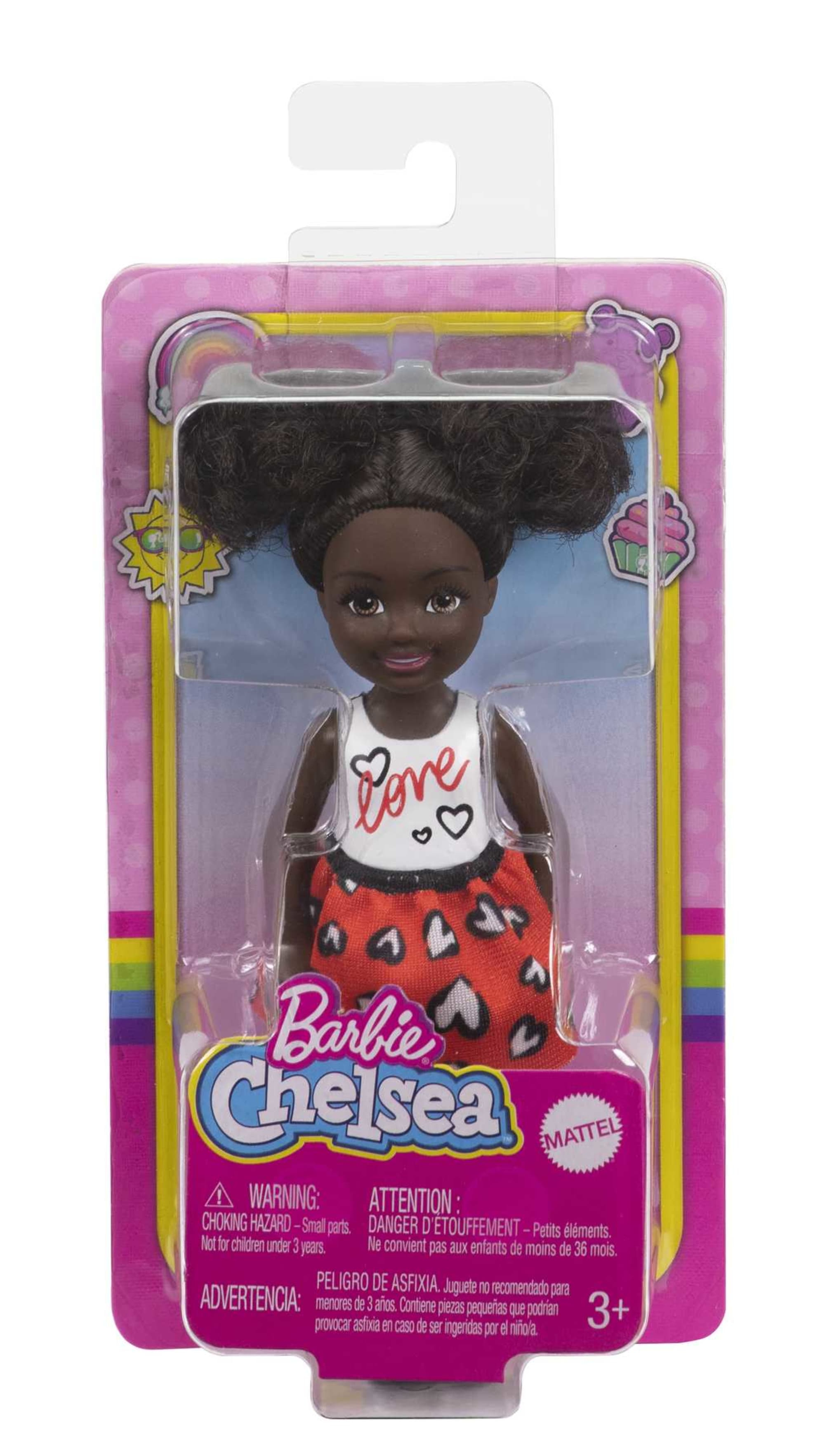 Eine Barbie Chelsea-Puppe in einer Verpackung. Sie trägt ein weißes Oberteil mit 'Love' und einen roten Rock mit Herzen. Die Verpackung ist rosa.