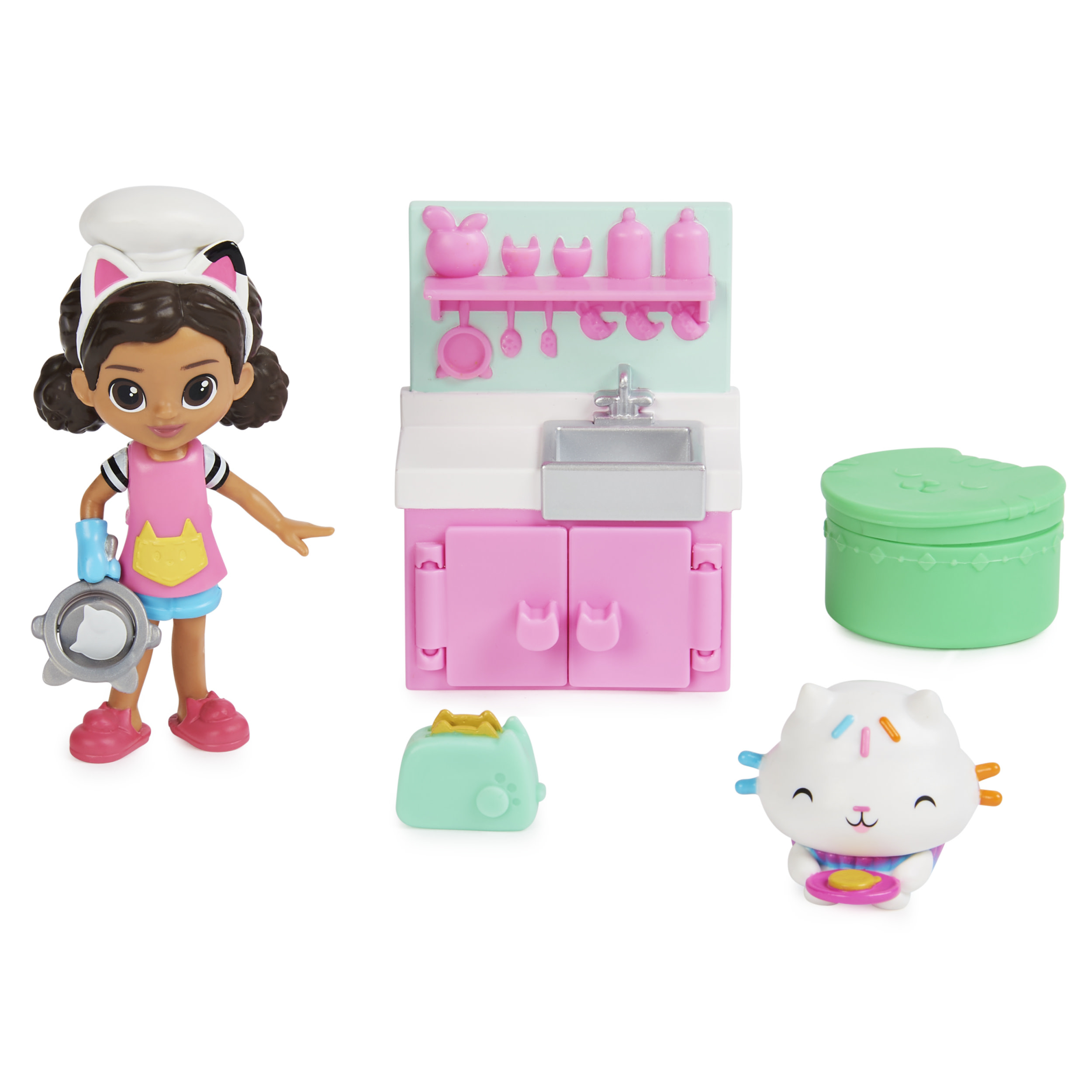 Ein Spielzeugset mit einer Puppe mit Kochmütze, Küchenset, grüner Box, katzenförmiger Figur und Toaster.