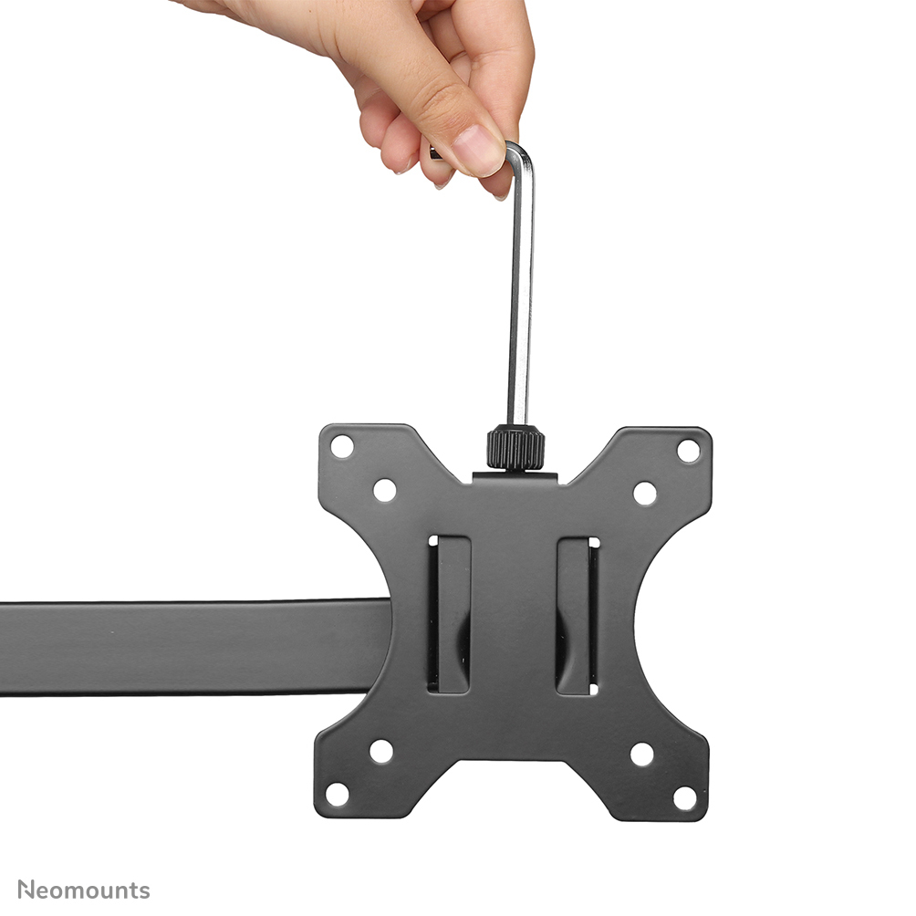 Eine Hand hält ein silbernes Werkzeug über einer schwarzen Metallhalterung. Die Halterung hat Löcher und Schlitze, mit einem Arm.