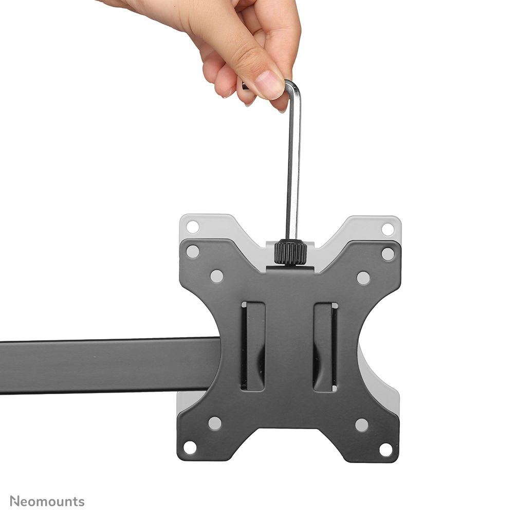 Eine Hand hält einen silbernen Sechskantschlüssel über einer schwarz-grauen Monitorhalterung. Die Halterung hat Löcher und einen horizontalen Balken.