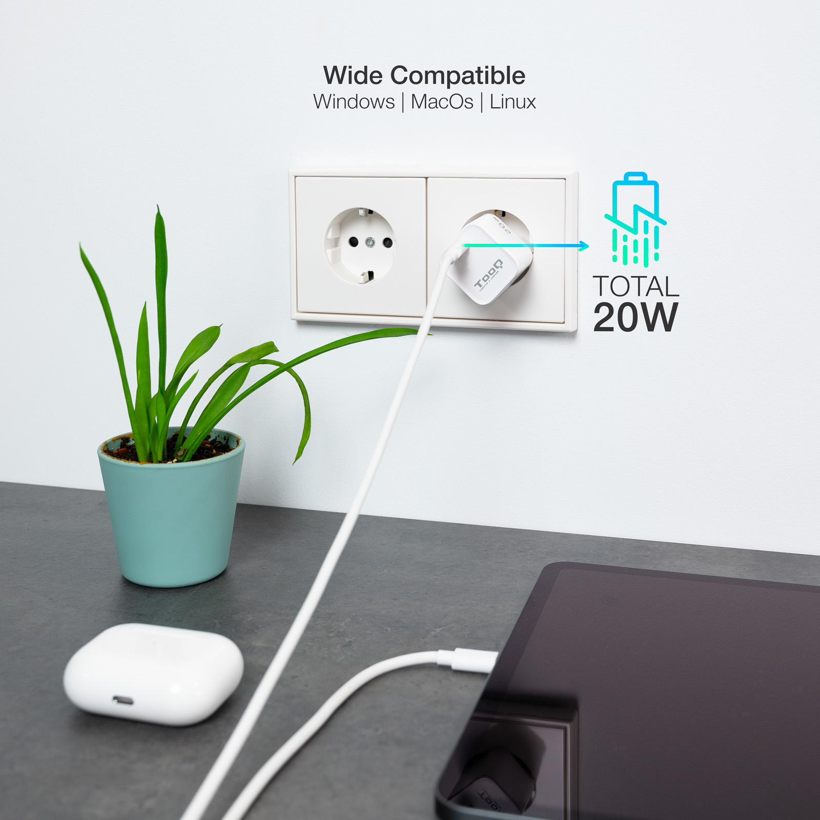 Un cargador blanco está enchufado a una toma de corriente, alimentando una tableta. Hay una planta y auriculares cerca.