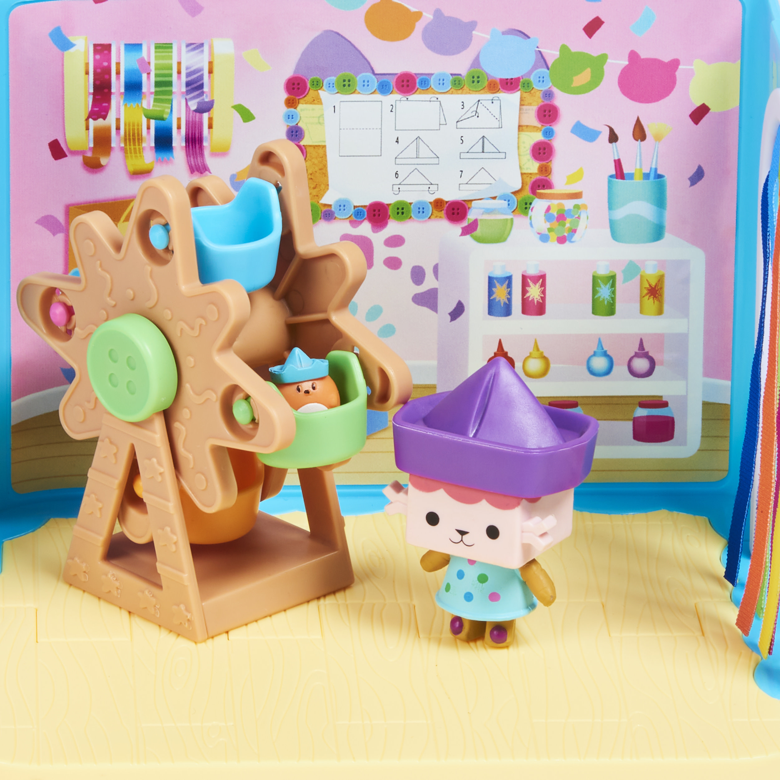 Spielzeugszene mit Riesenrad, Figur und Bastelbedarf auf Regalen. Rosa und blauer Hintergrund.