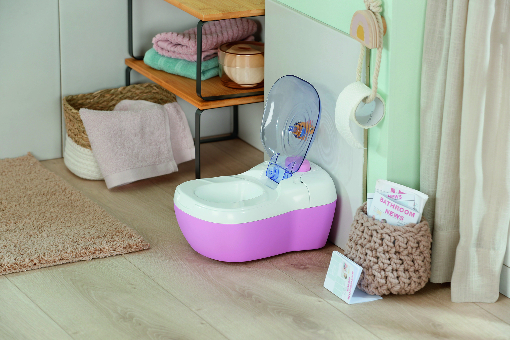 Naczynie nocne dla dziecka z otwartą pokrywą. Ręczniki na półkach, dywan i pleciony kosz z gazetami w łazience.